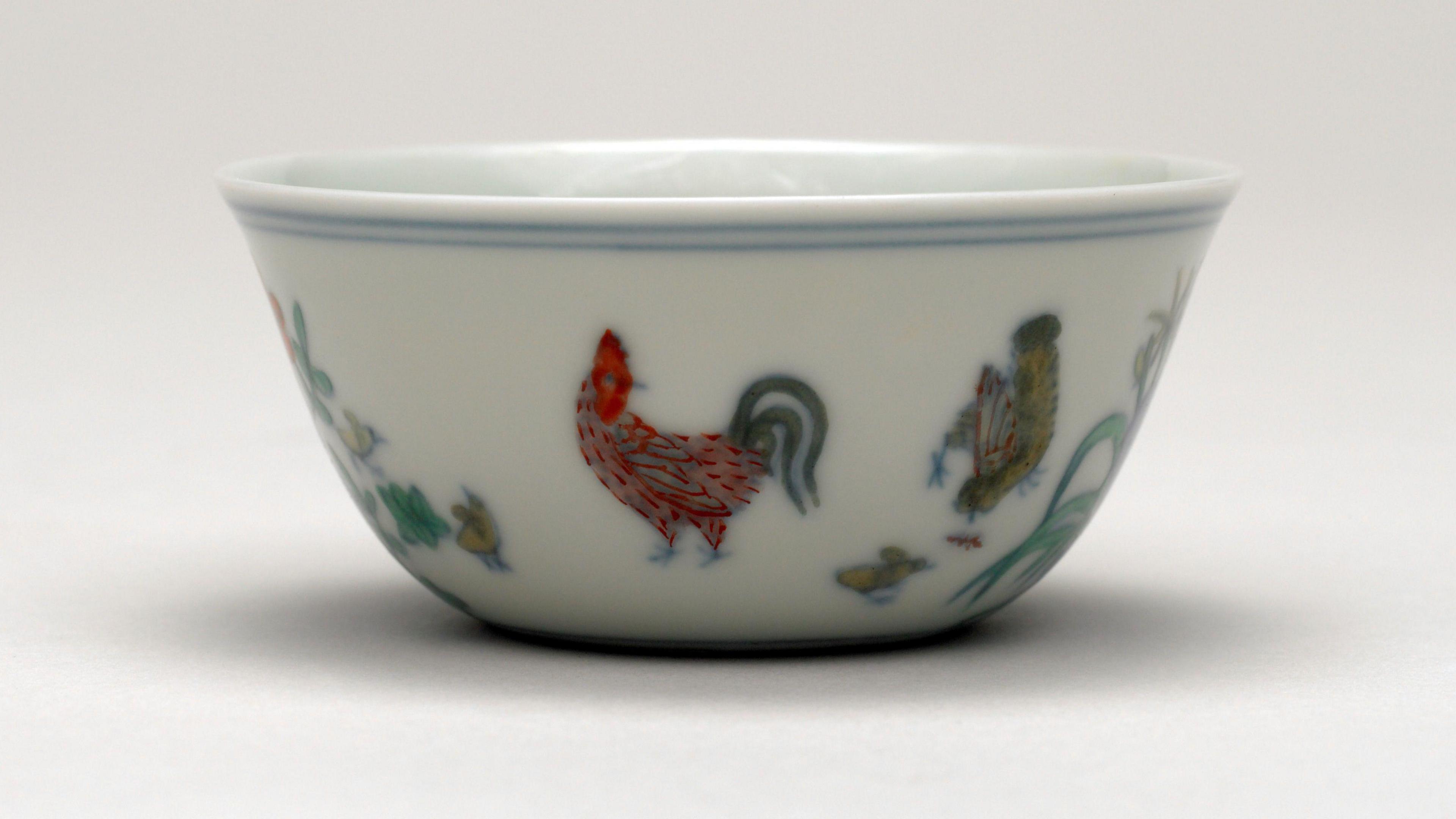 A white ceramic Doucai 'chicken cup' which is imprinted with images of a cockerel and hens