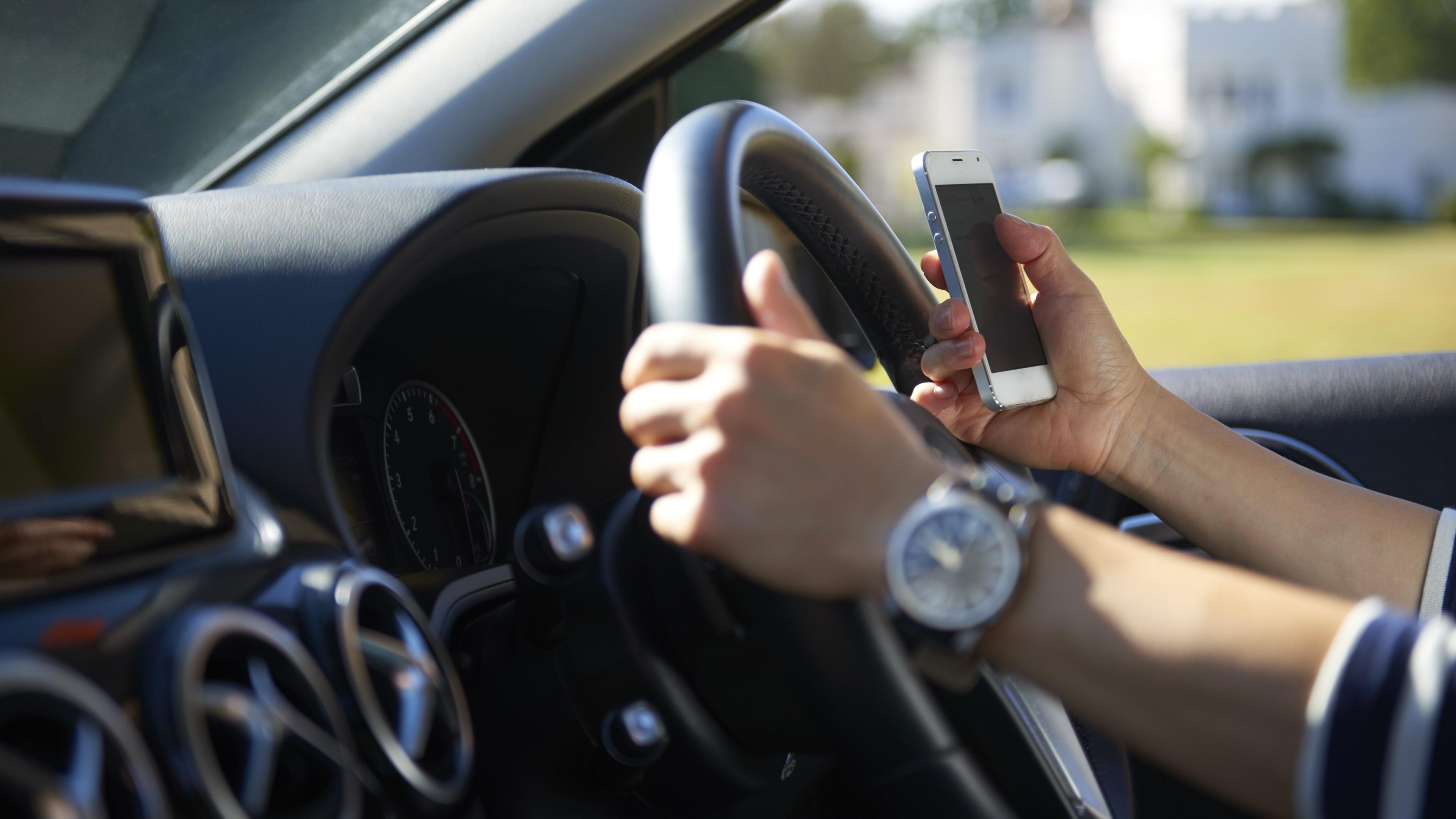 Woman using a mobile phone while driving - stock shot