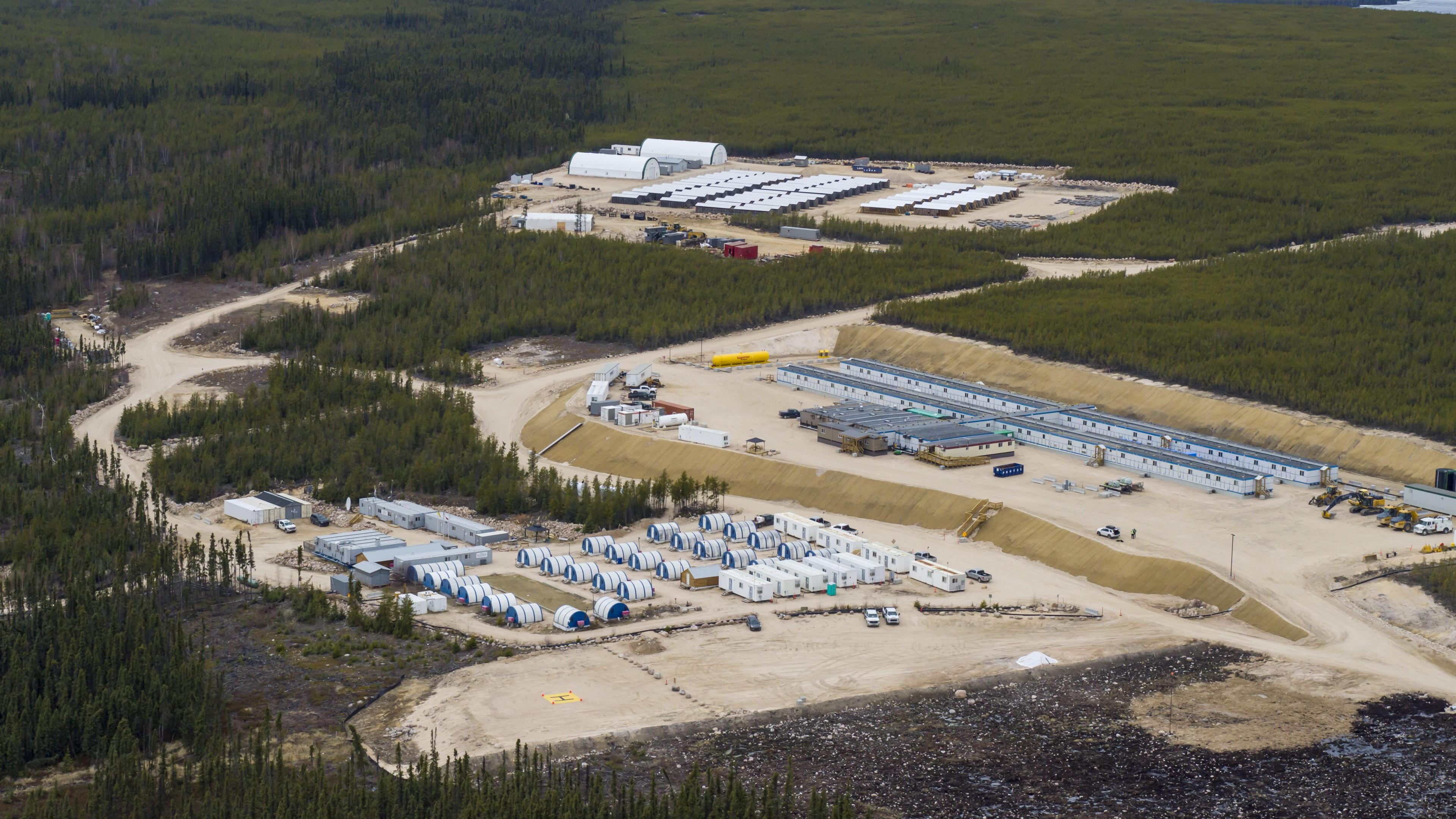 An aerial photo of the site of NexGen's mine in the Athabasca Basin in northern Saskatchewan. The landscape is mostly forested, with work structures nestled on cleared land in the middle. 