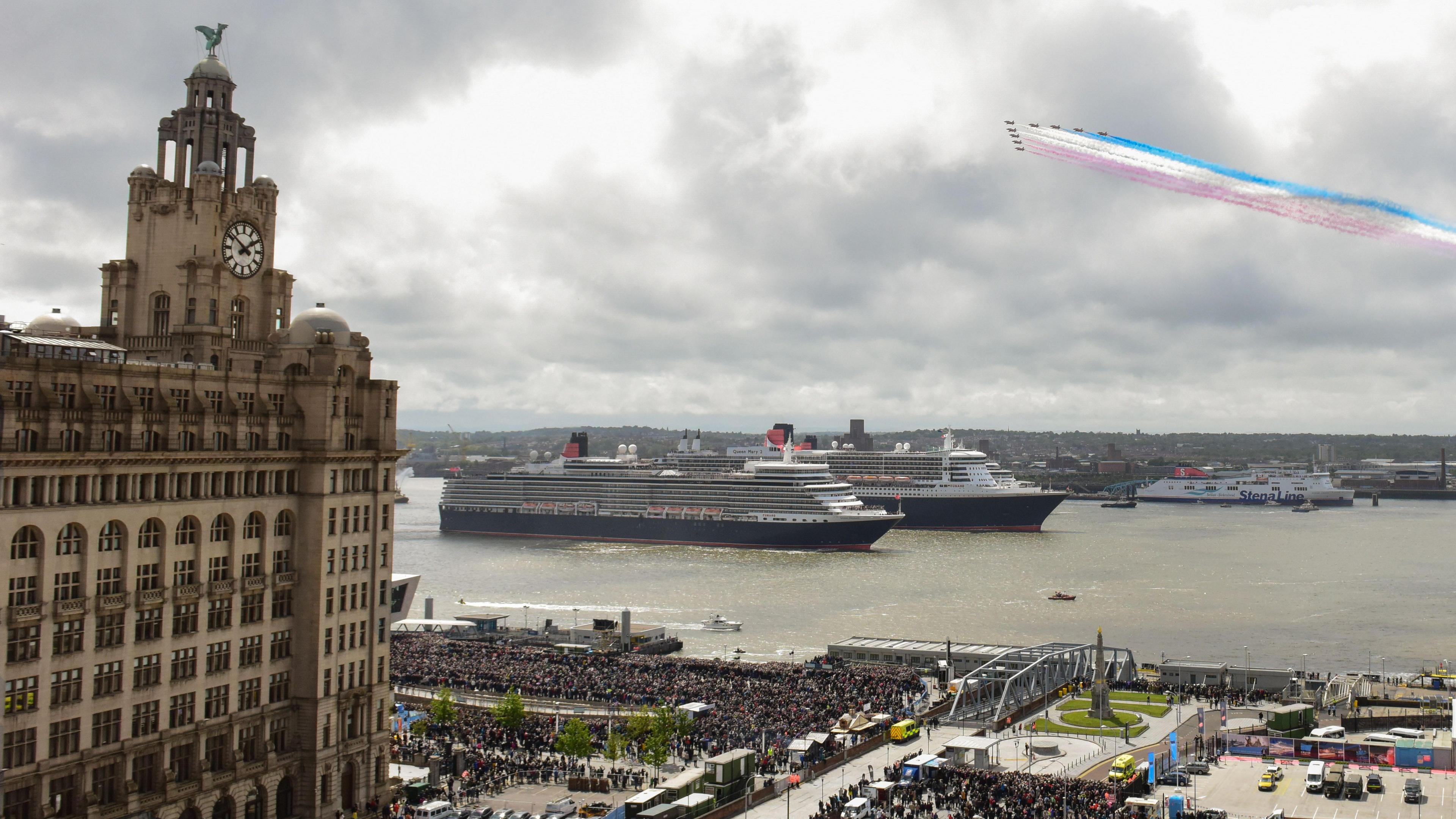 Cunard cruise liners sailing on the River Mersey near the Royal Liver Building and thousands of people lining Liverpool's waterfront while the Red Arrows performed a fly-past to celebrate Cunard's 175th anniversary.