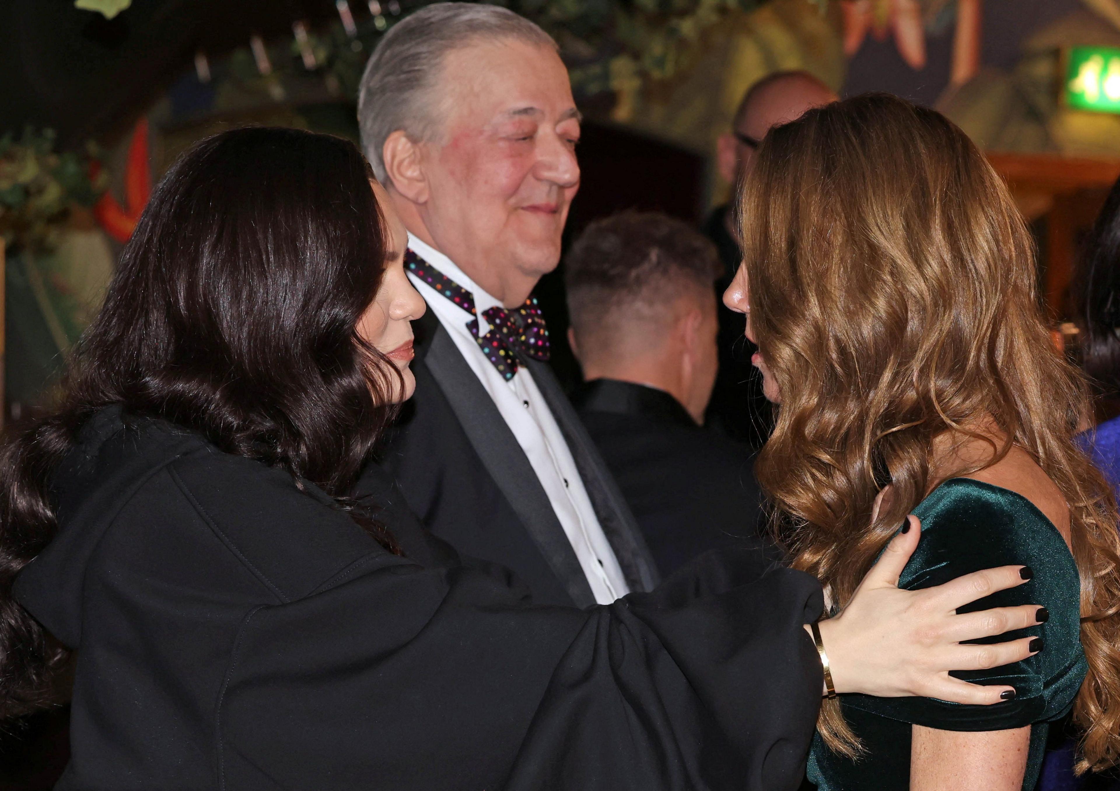 Jessie J with her hands on the Princess of Wales's shoulders as they are in conversation, with Stephen Fry in the background slightly smiling 