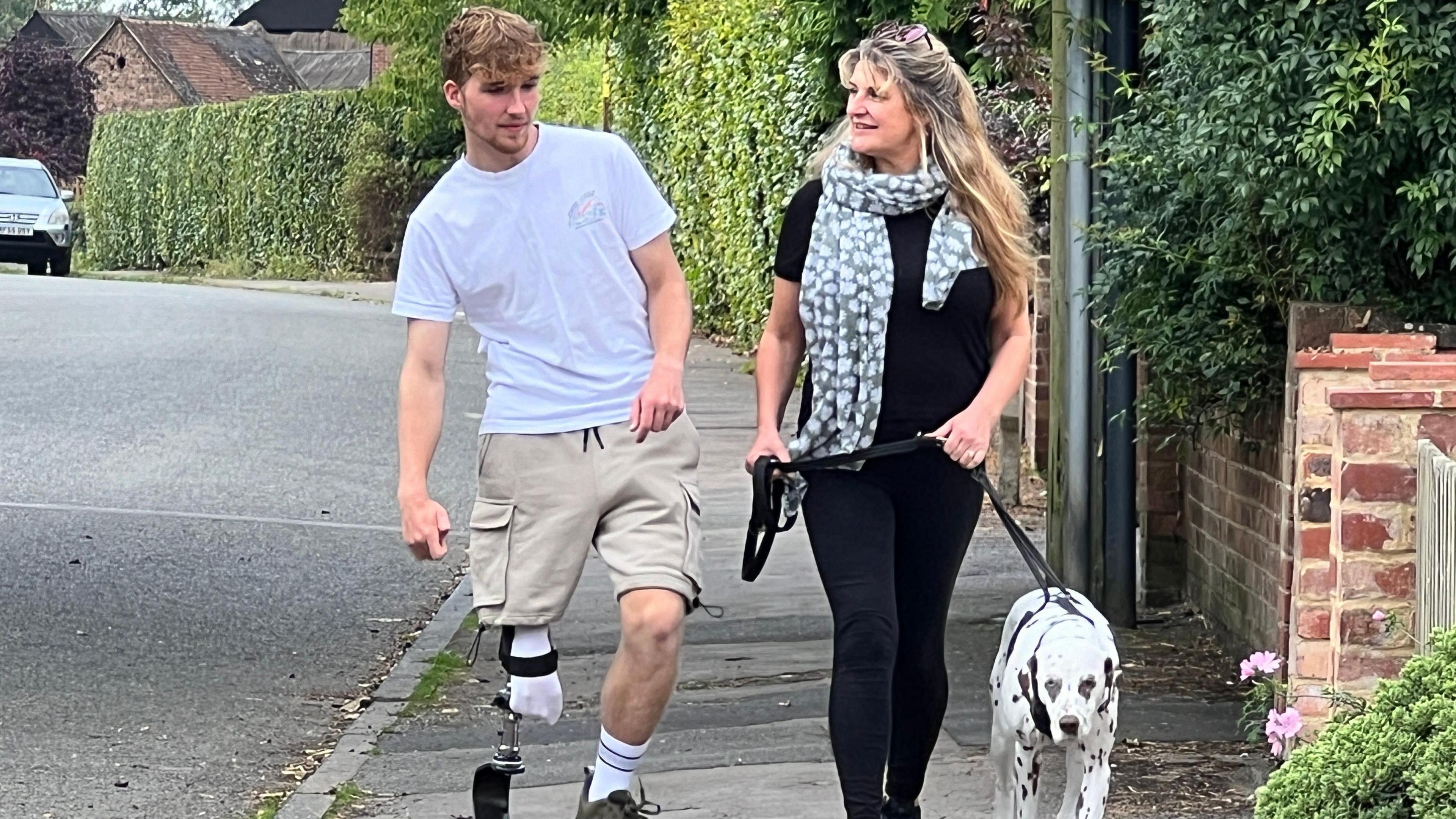 Ollie walking with his mum Carly and their Dalmatian down a pavement next to a road