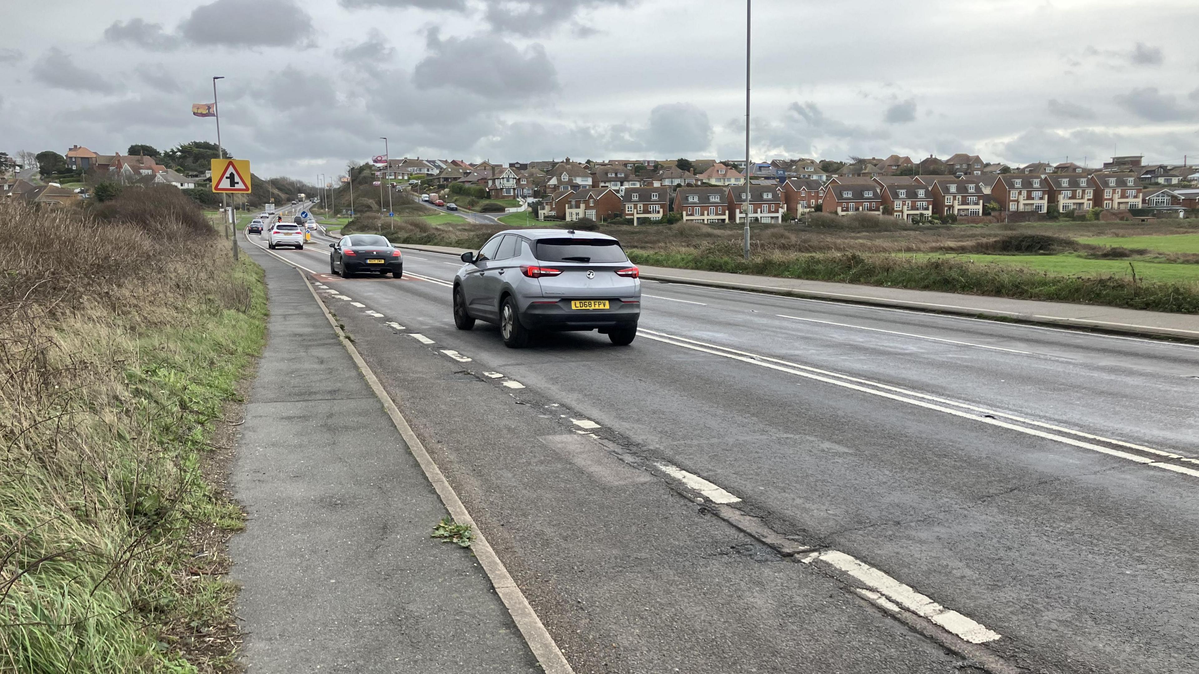 A line of cars driving along the A259 road in Newhaven in the direction of Seaford on a grey cloudy day. 
