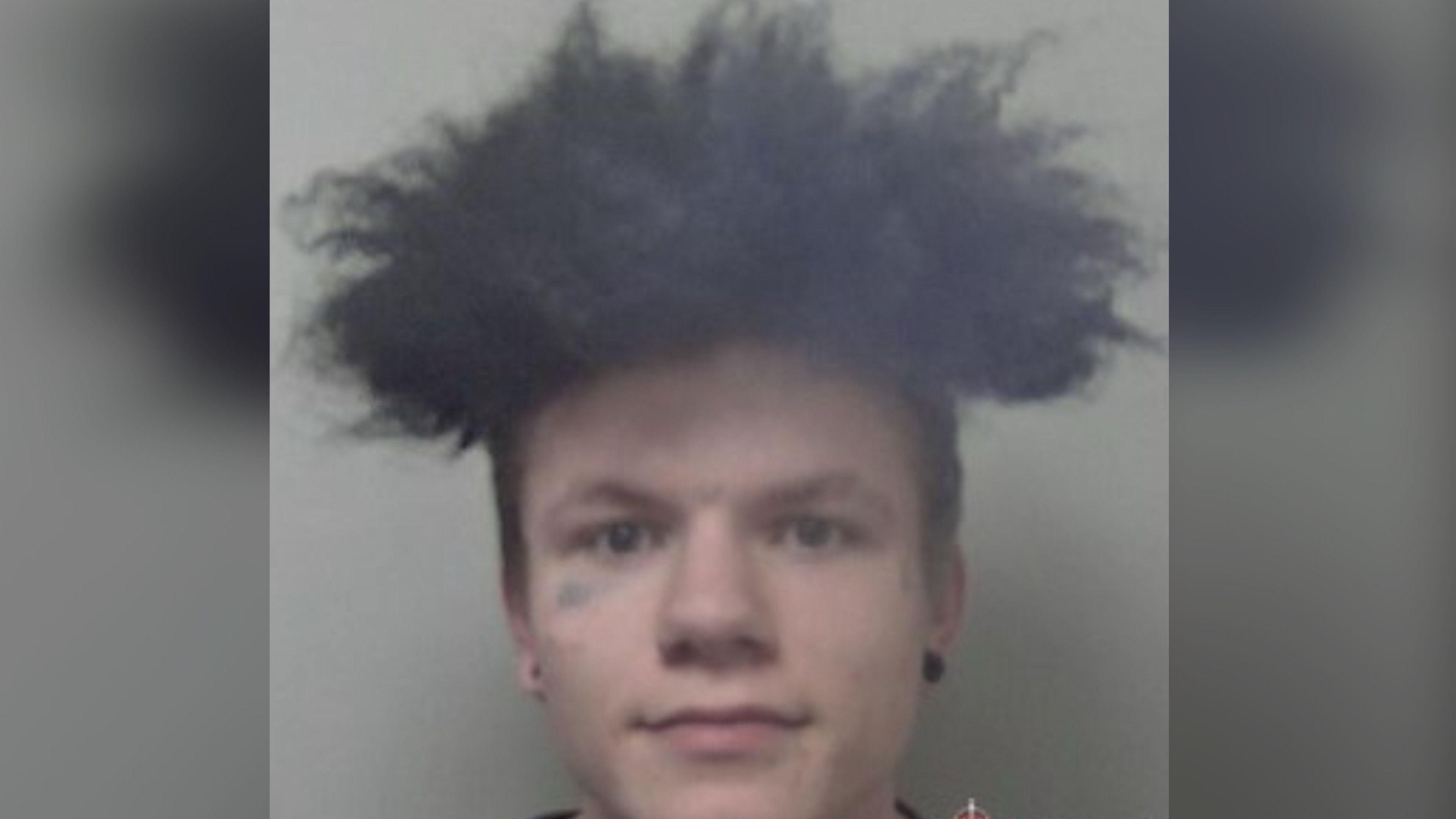 A man dark hair and wearing black studs.