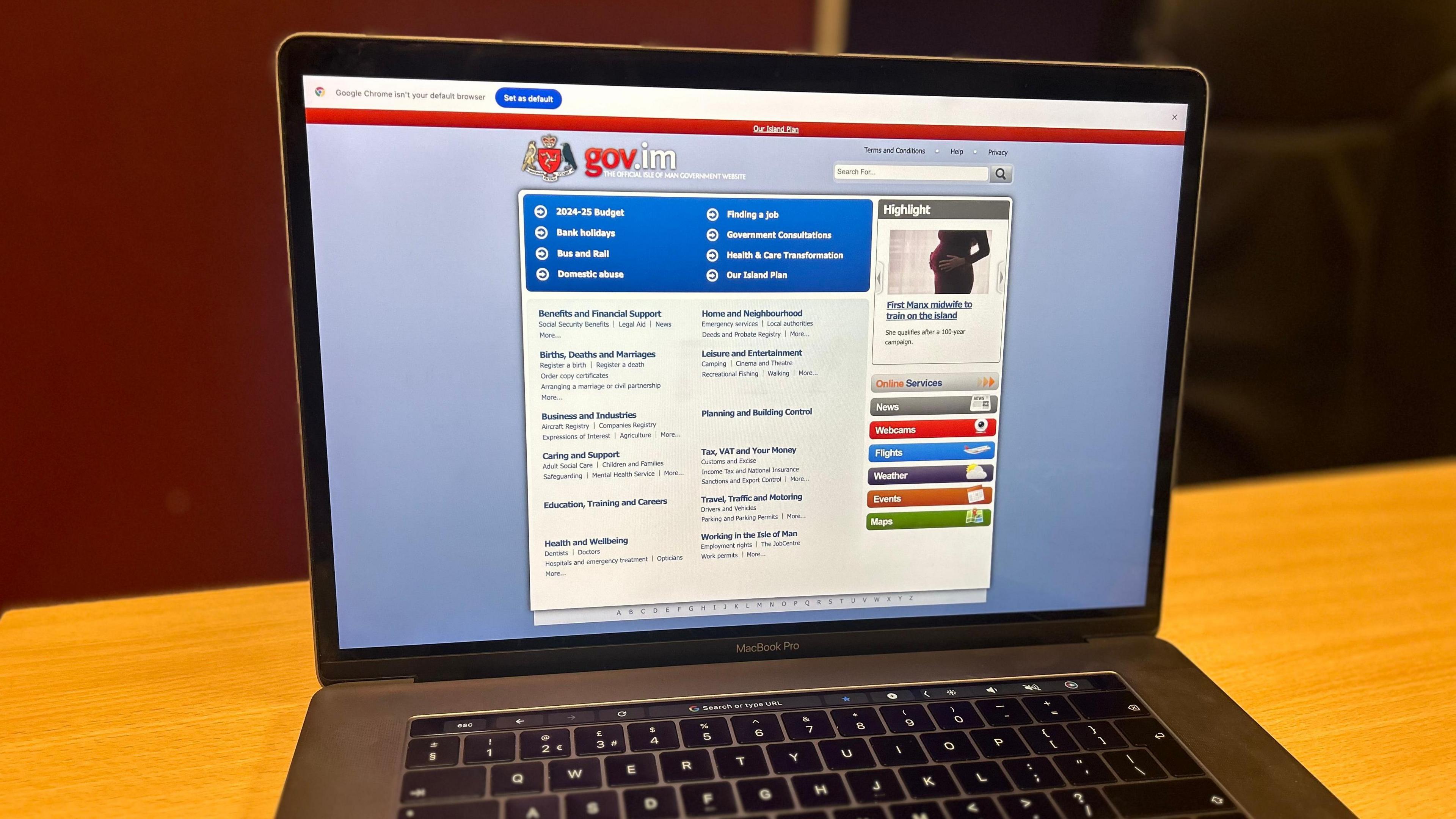 A laptop showing the government website, which is predominately blue with the government crest and gov.im at the top.
