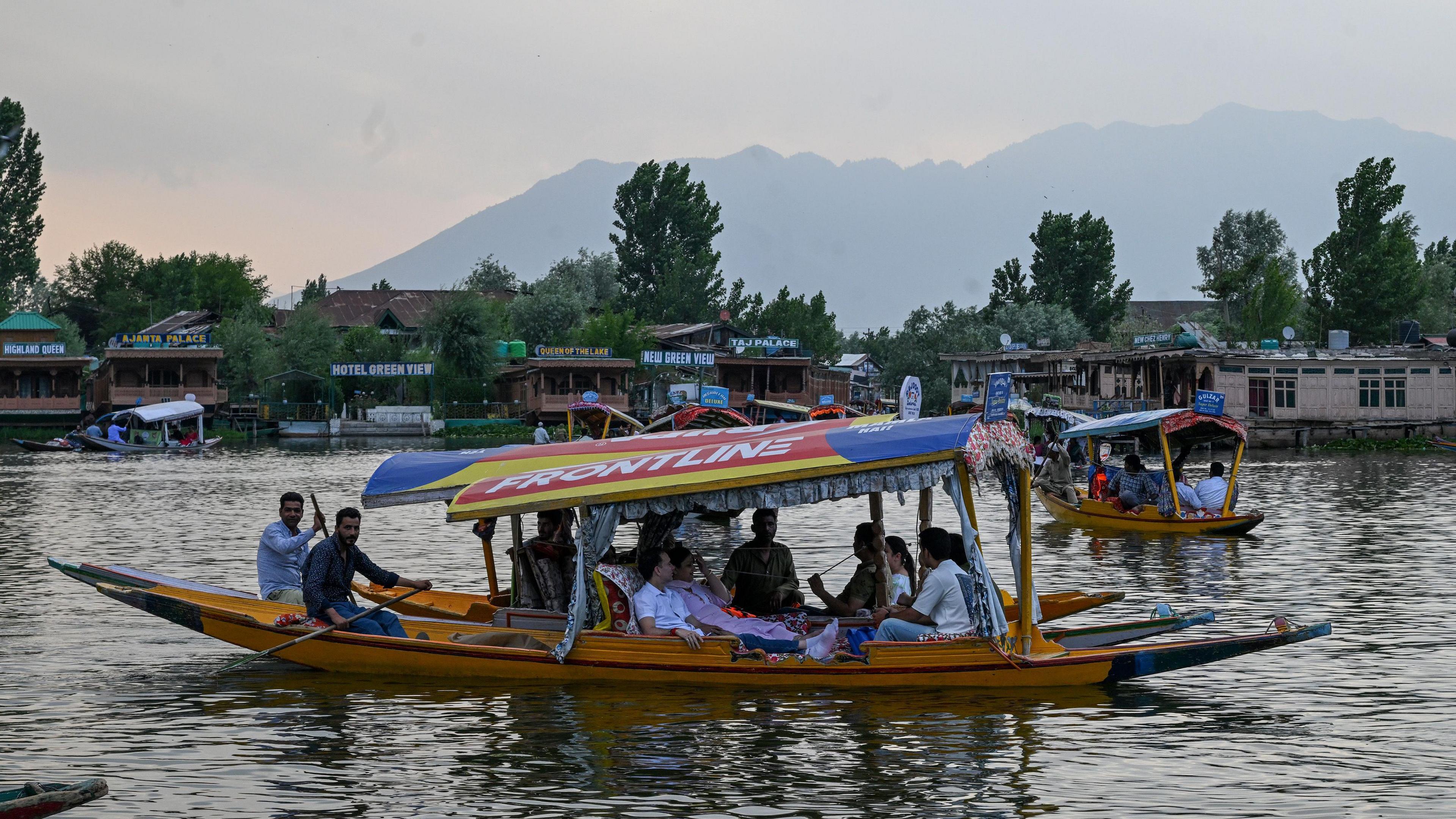 Tourists enjoying a ride on a shikara - traditional colourful narrow boats made with wood - in Srinagar's Dal Lake