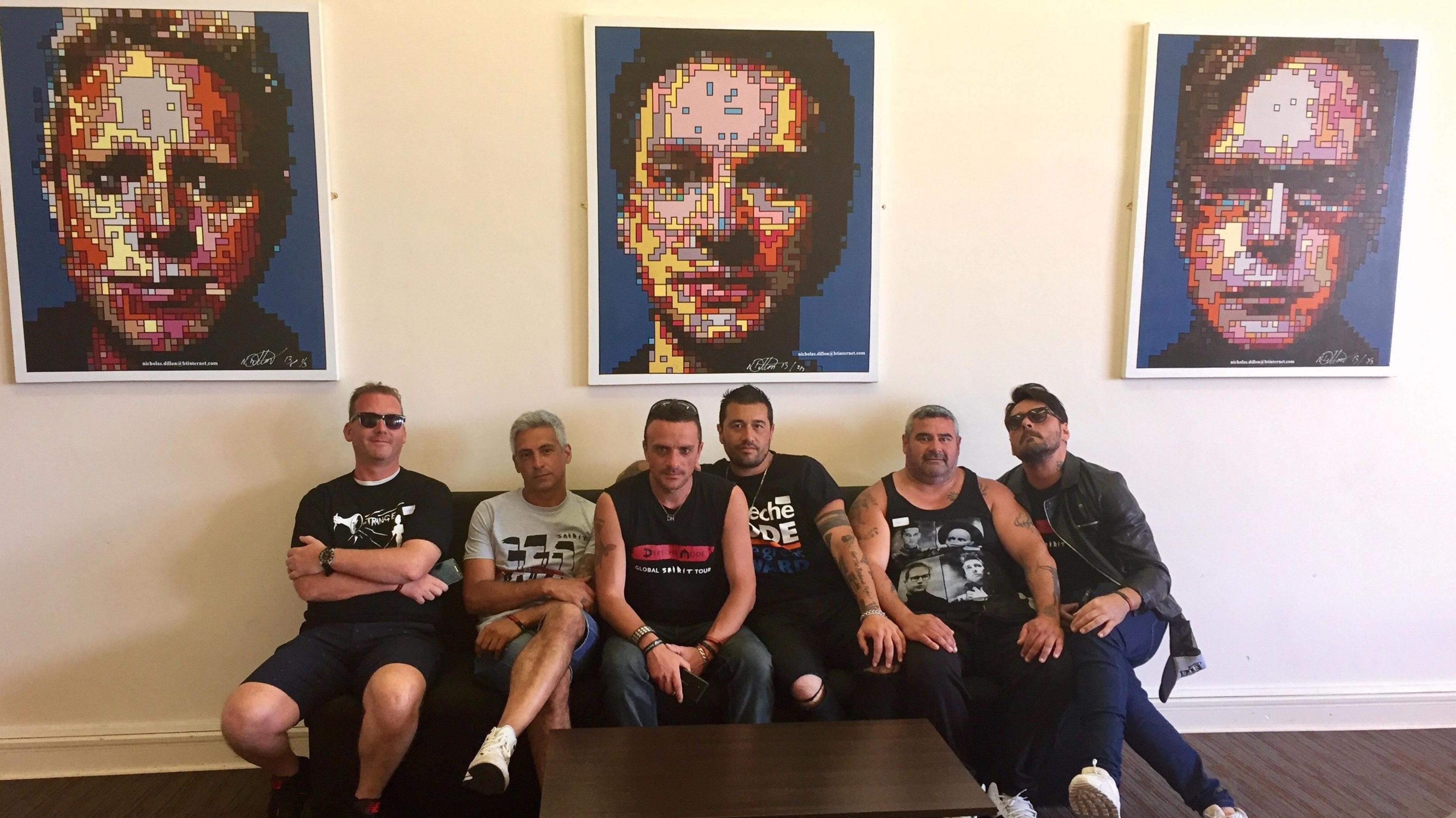 Six men, wearing Depeche Mode T-shirts, sit on a sofa in front of pixelated portraits of Gore, Gahan and Fletcher.