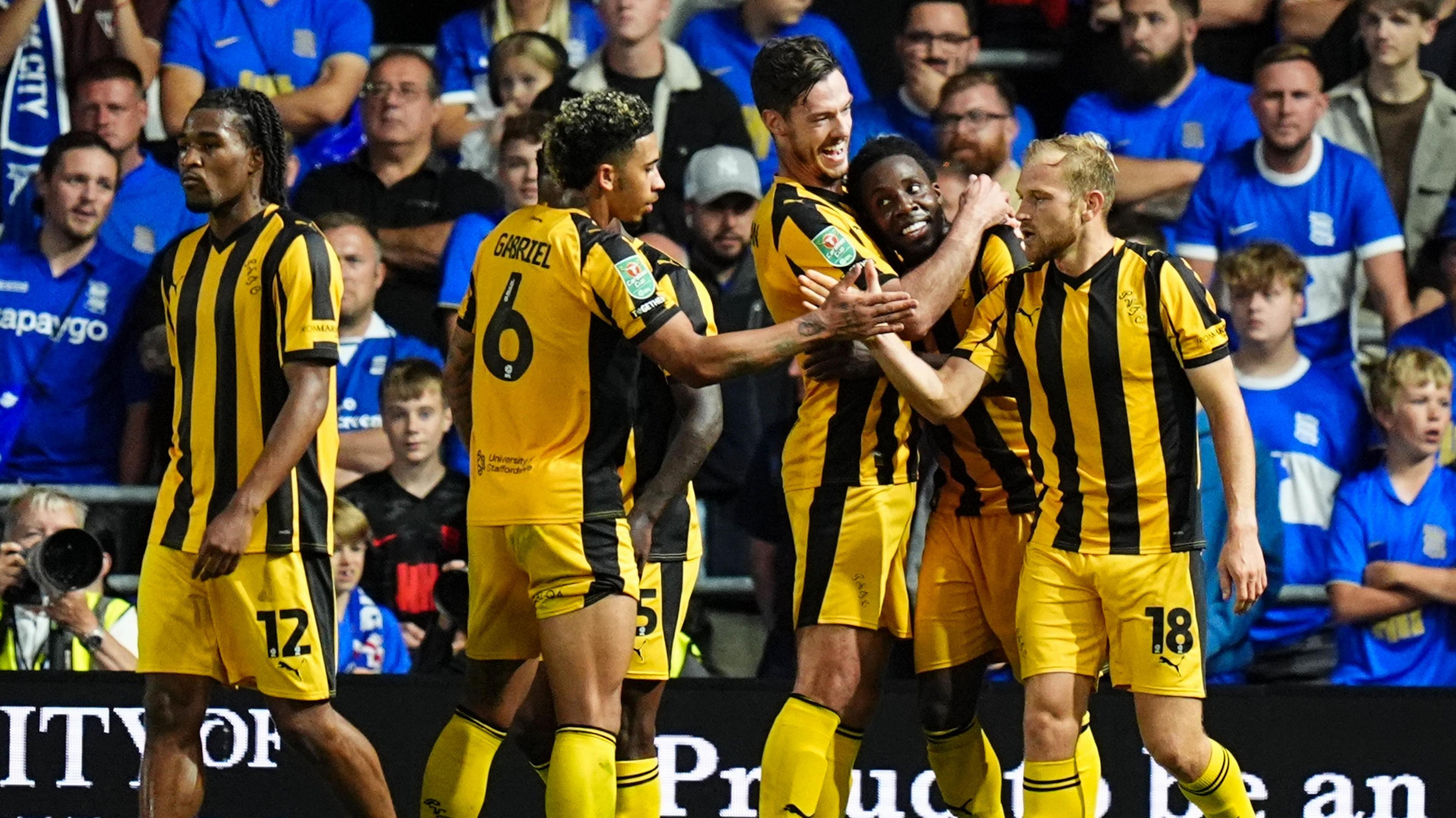 Jaheim Headley (second right) is hugged by a team-mate as two more team-mates clasp hands in front of him after scoring a goal