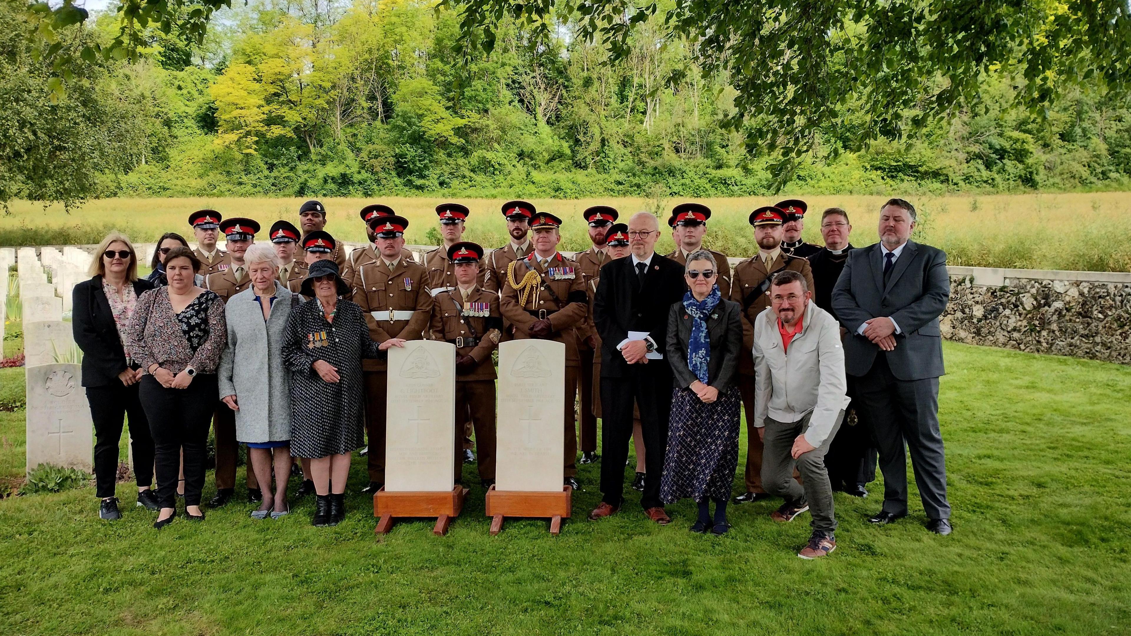 Families and soldiers gathered around two graves