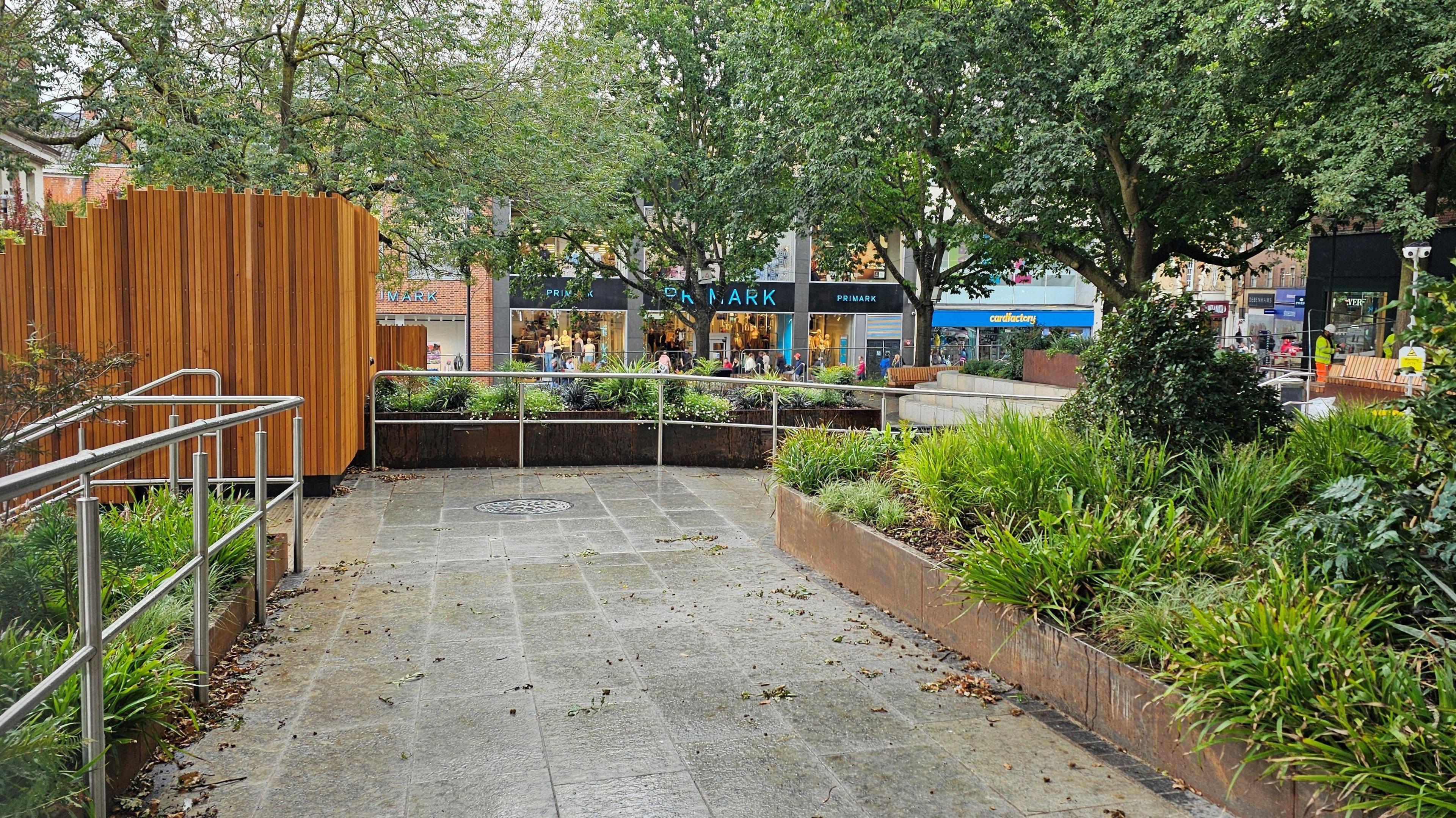 This image shows the redevelopment of Hay Hill, with new paving, some wooden fencing and planters with a range of plants.