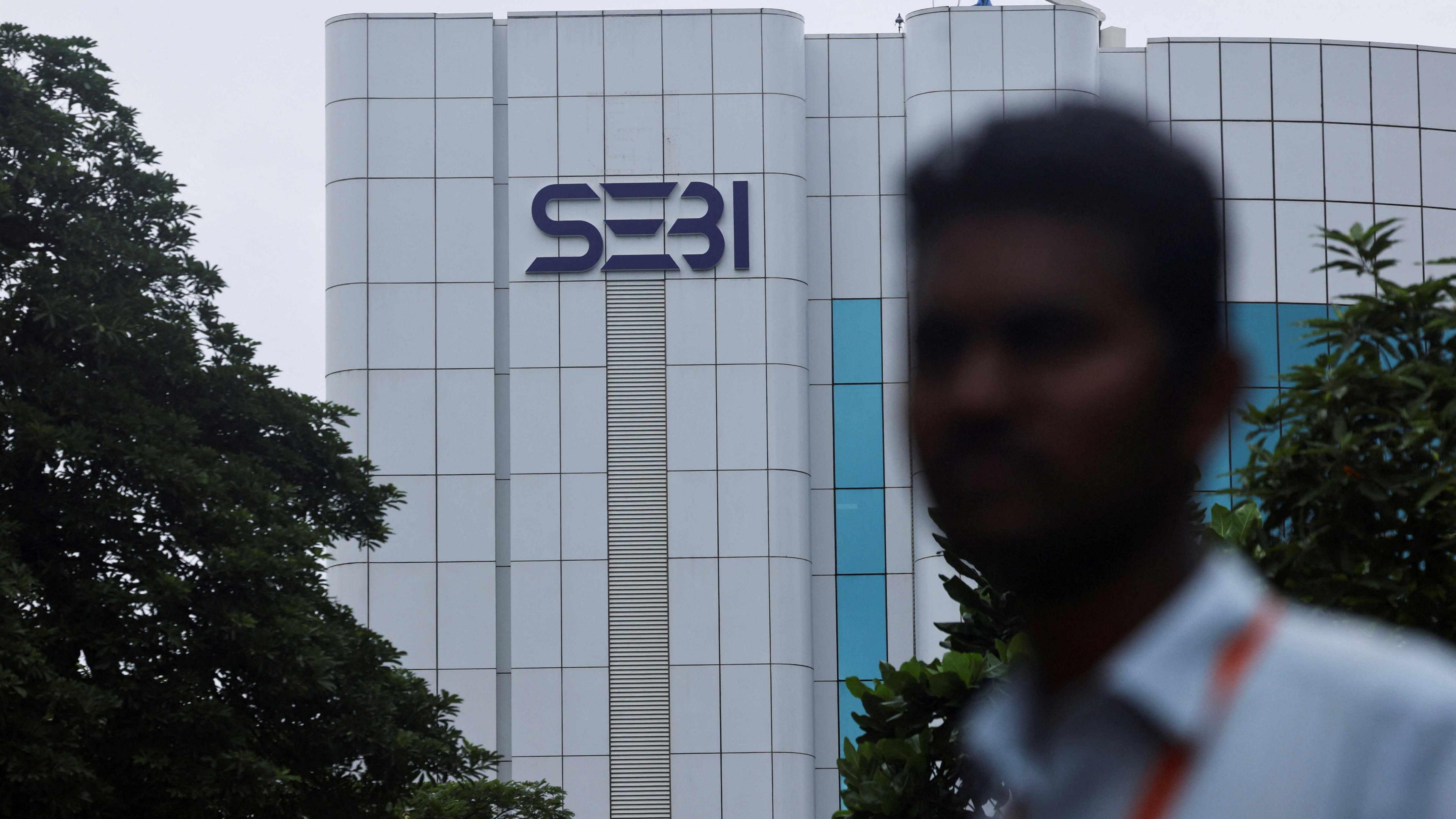 A man stands in front of a logo of the Securities and Exchange Board of India (SEBI) headquarters in Mumbai, India, September 6, 2024.