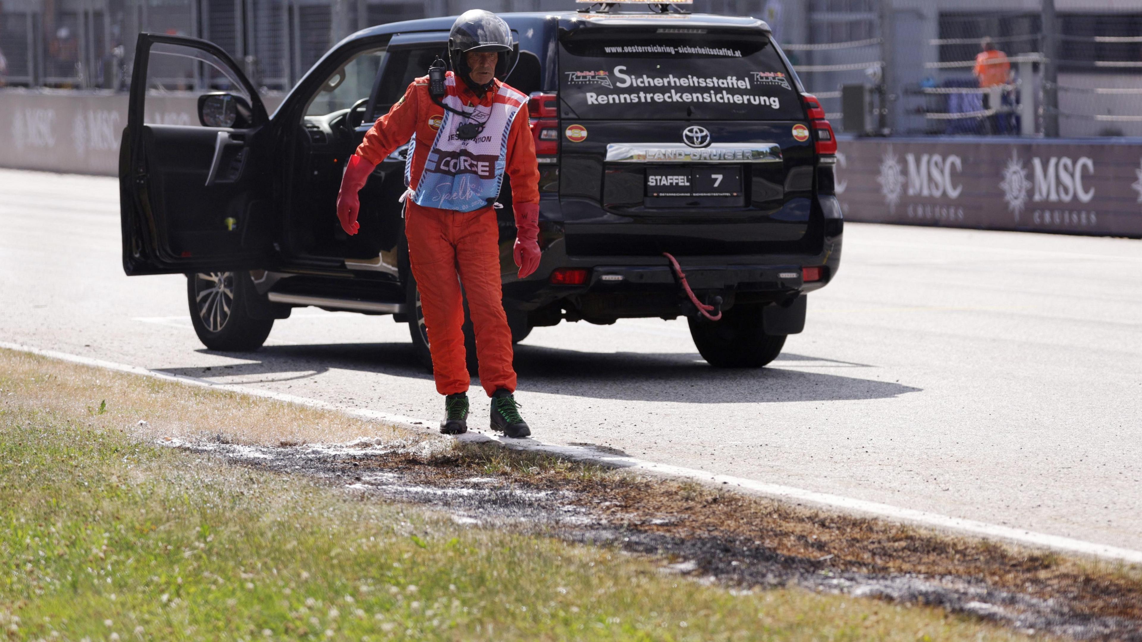 A marshal gets out of a vehicle to attend to a grass final coming out of the final corner during Austrian Grand Prix qualifying