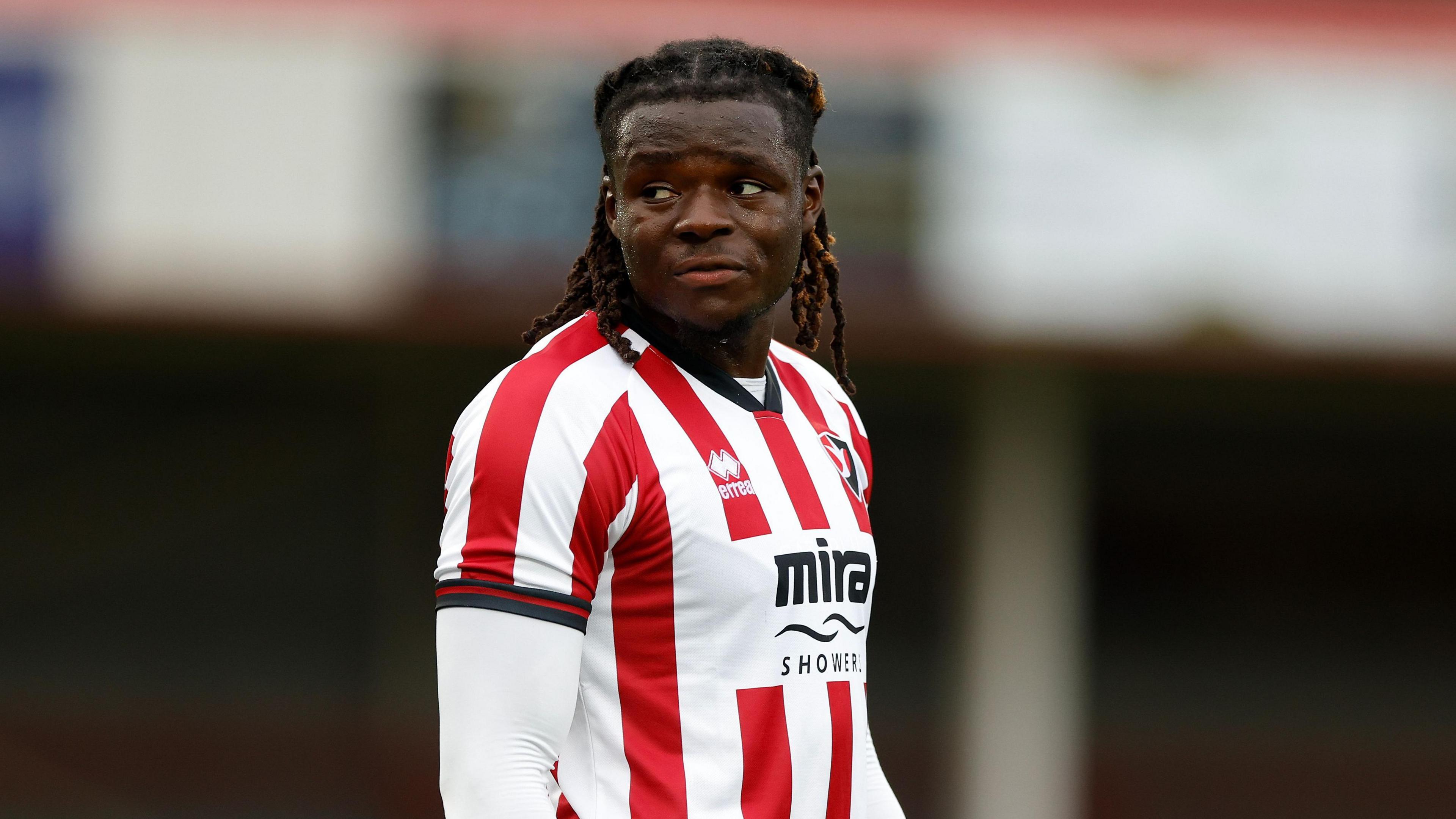 Ibrahim Bakare standing on the pitch with his arms by his side during a pre-season match for Cheltenham