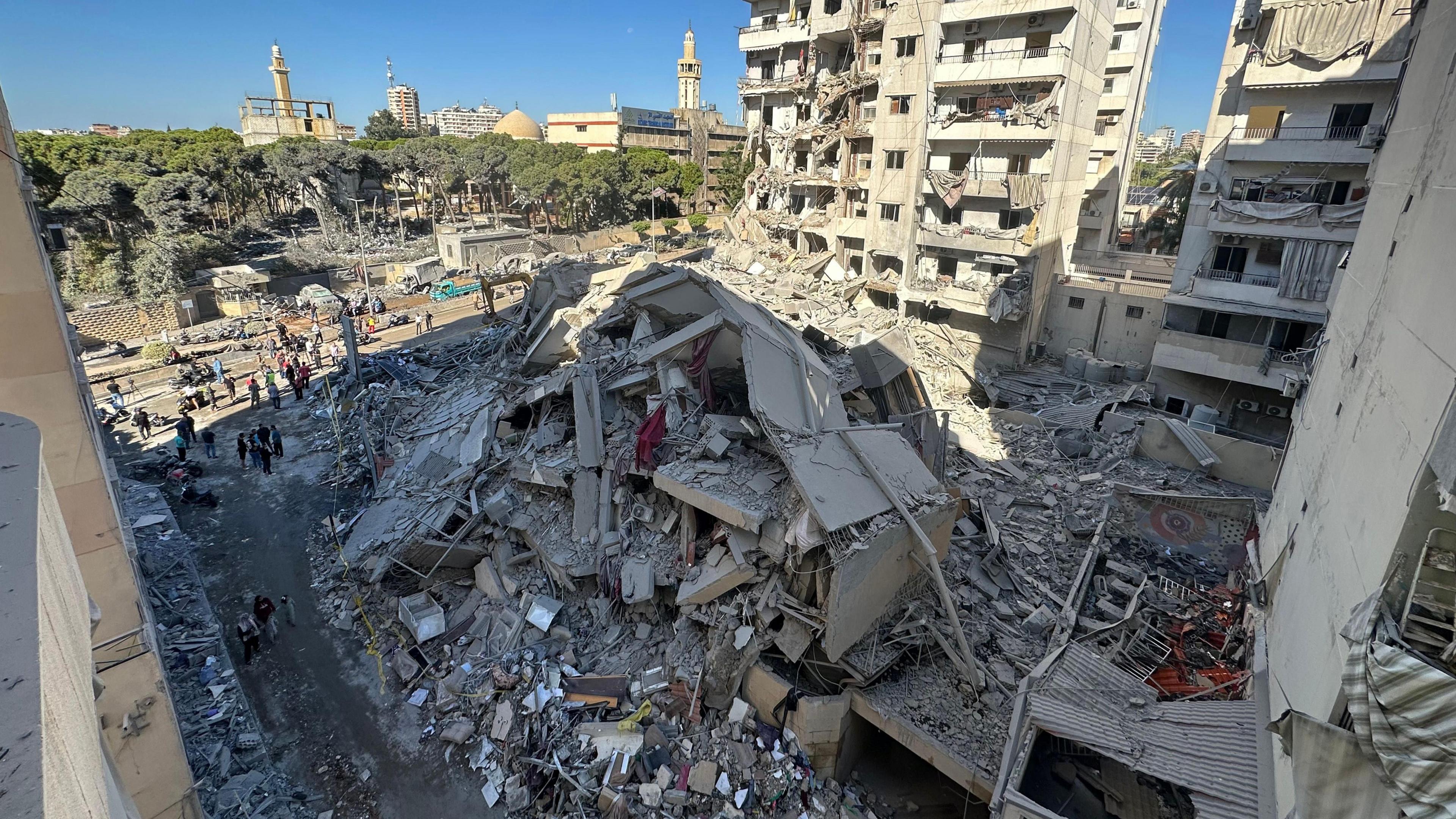 People inspect a destroyed building in the Beirut suburb of Chiyah, Lebanon, following an Israeli strike that targeted a branch of the Hezbollah-linked Al-Qard Al-Hassan financial association (21 October 2024)