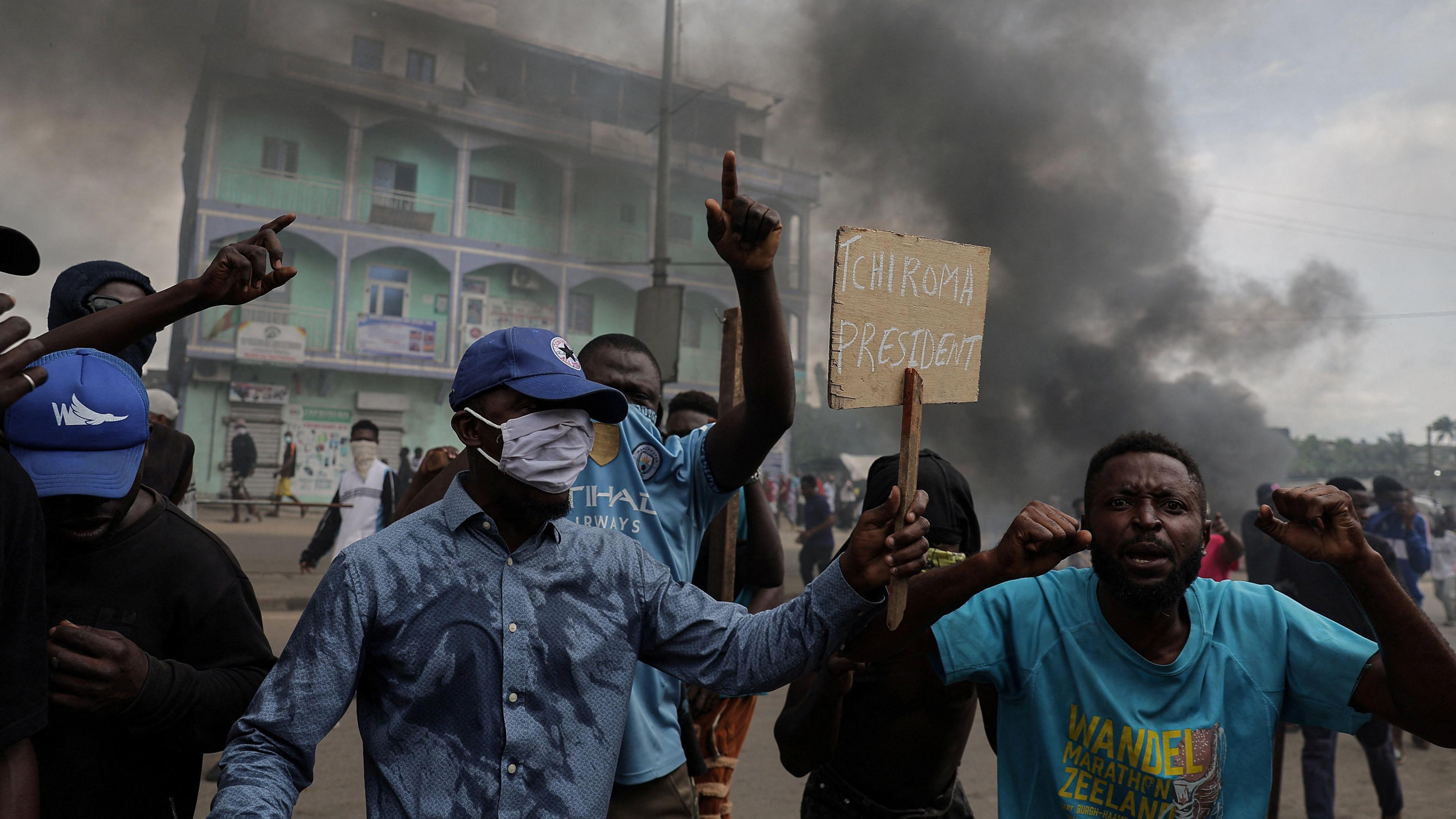 A man holds a sign as supporters of Cameroon opposition candidate Issa Tchiroma clash with security forces, after the Constitutional Council declared President Paul Biya the winner of the October 12 presidential election, in Douala, Cameroon