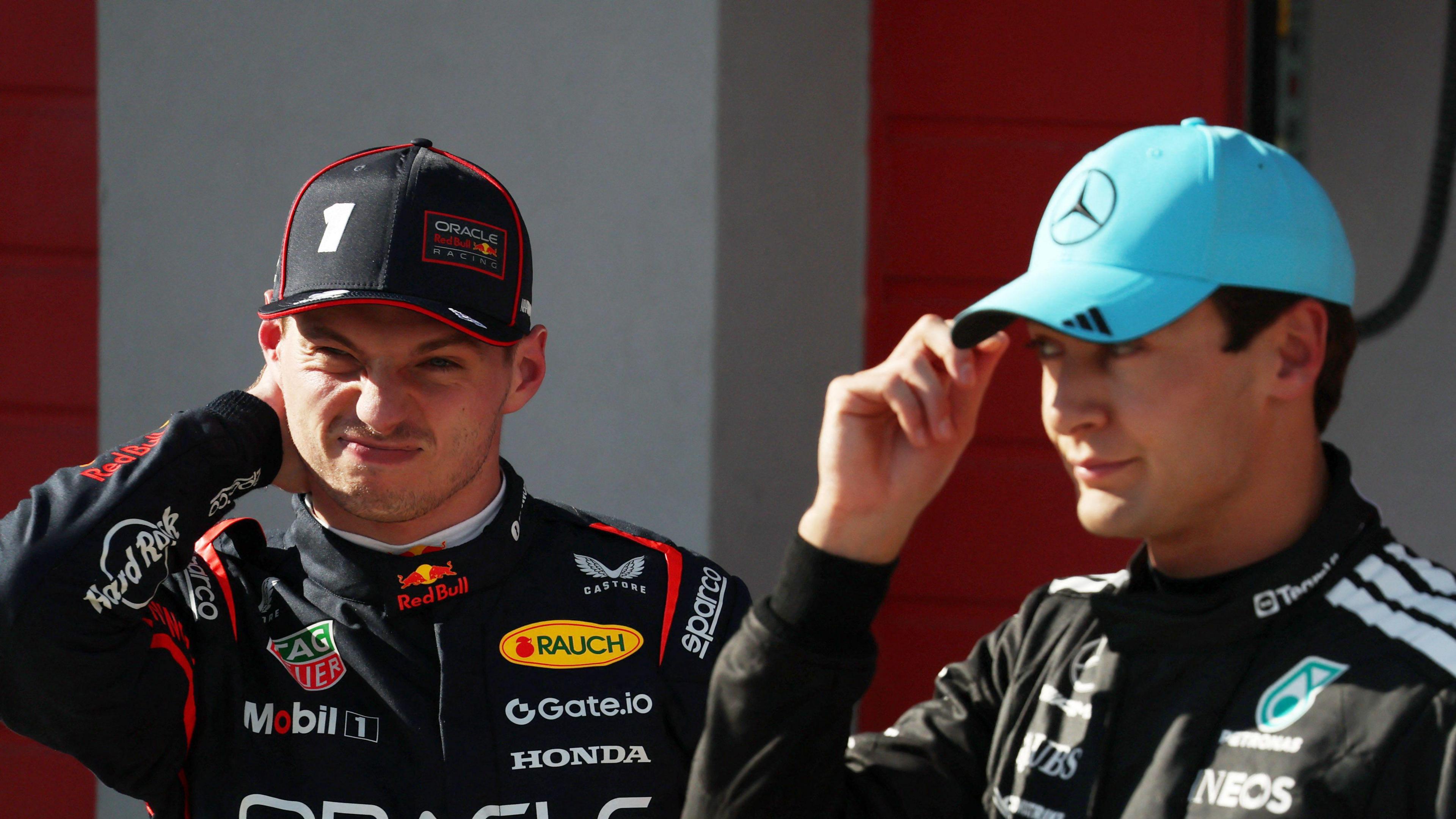 Max Verstappen scrunches up his face while stood next to George Russell, who is adjusting his cap, at the Emilia-Romagna Grand Prix at Imola in May 2025