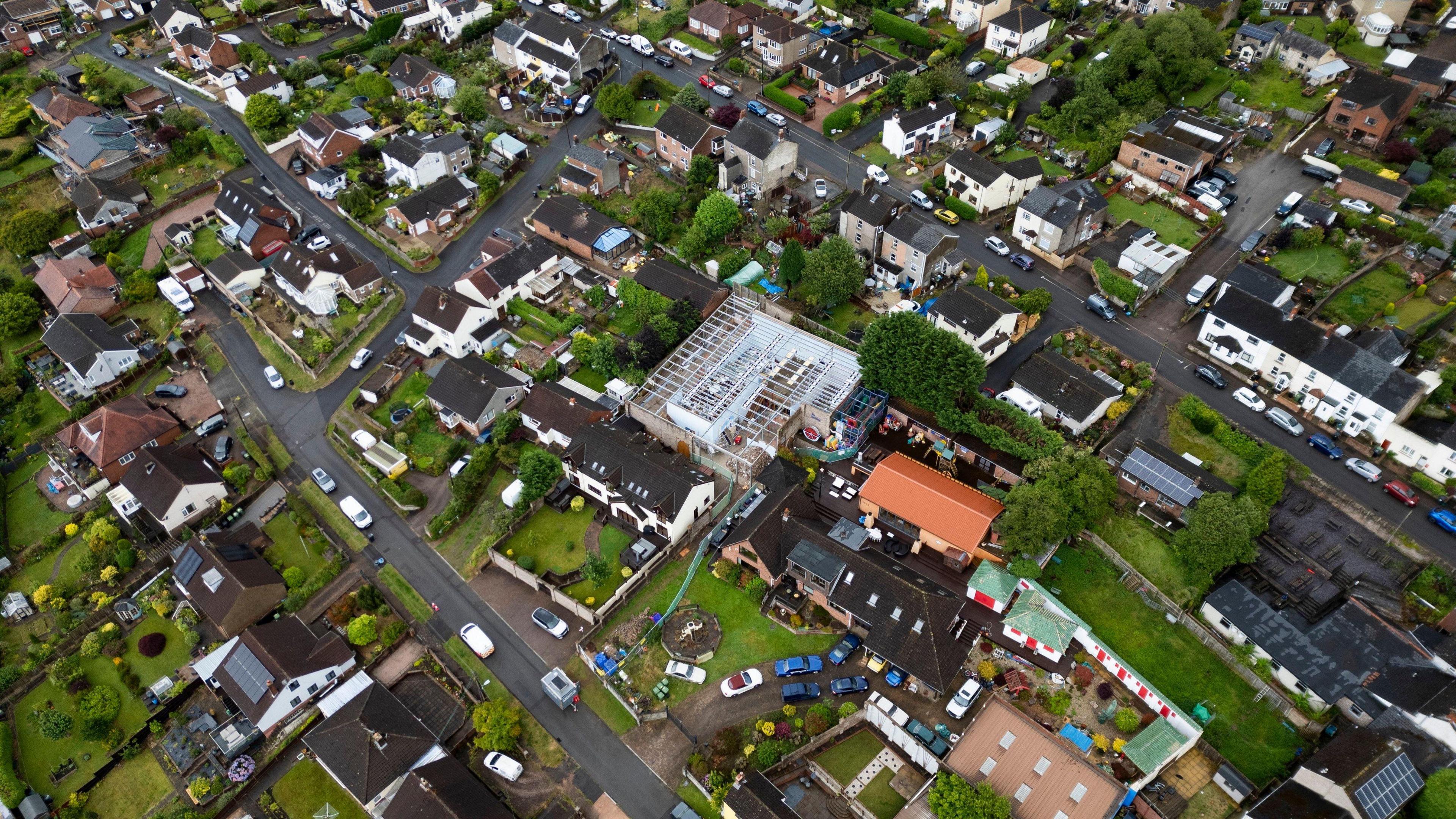 Aerial view of the mancave. The structure is in the middle of the picture and the roof is gone, exposing the foundations and interior of the building. Neighbouring houses, gardens and roads are surrounding it.