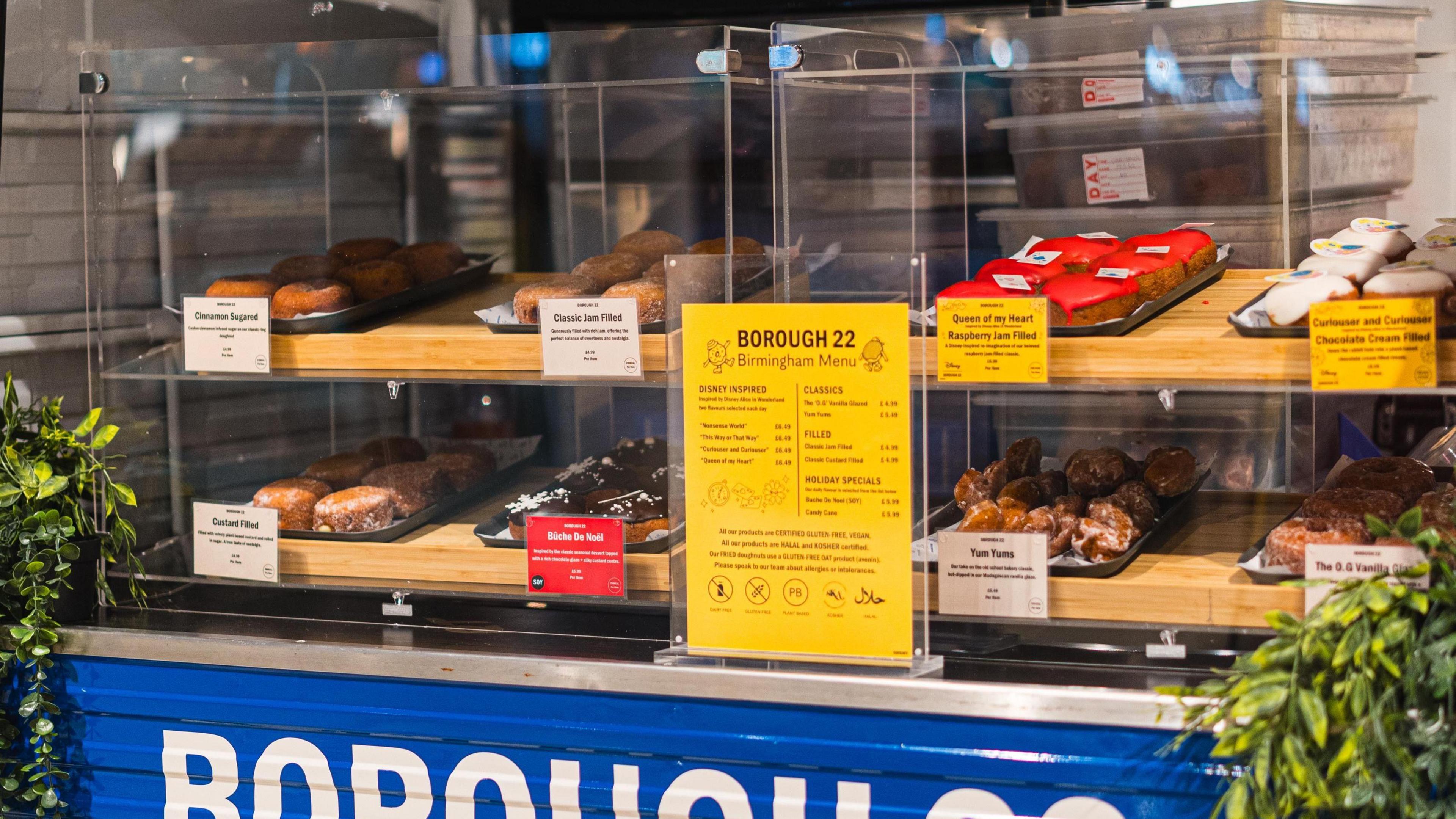 A stand of different coloured doughnuts with a blue sign saying 'Borough 22' in white writing on it.
