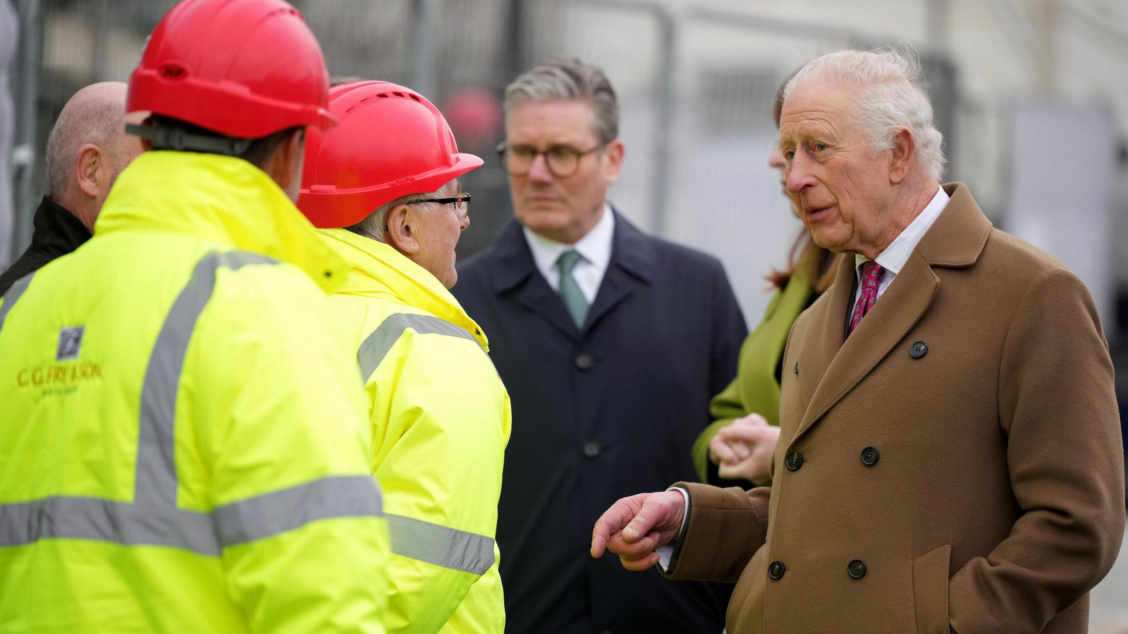 King Charles and Keir Starmer talking to building workers in high-vis jackets in Nansledan