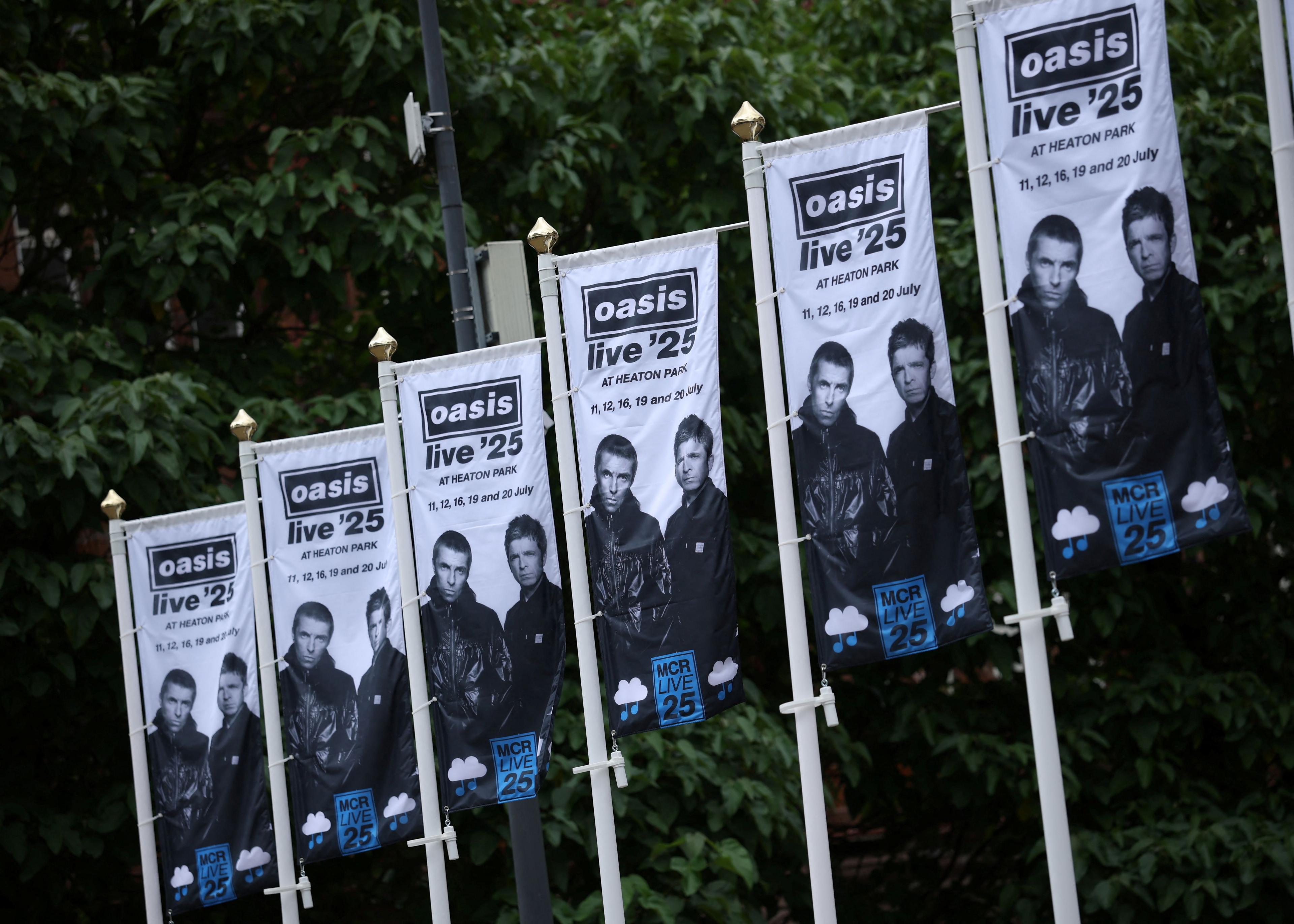 Oasis banners line the streets in Manchester ahead of the band's shows. The promotional banners are black and white with the band's Oasis logo at the top and an image of Noel and Liam at the bottom.