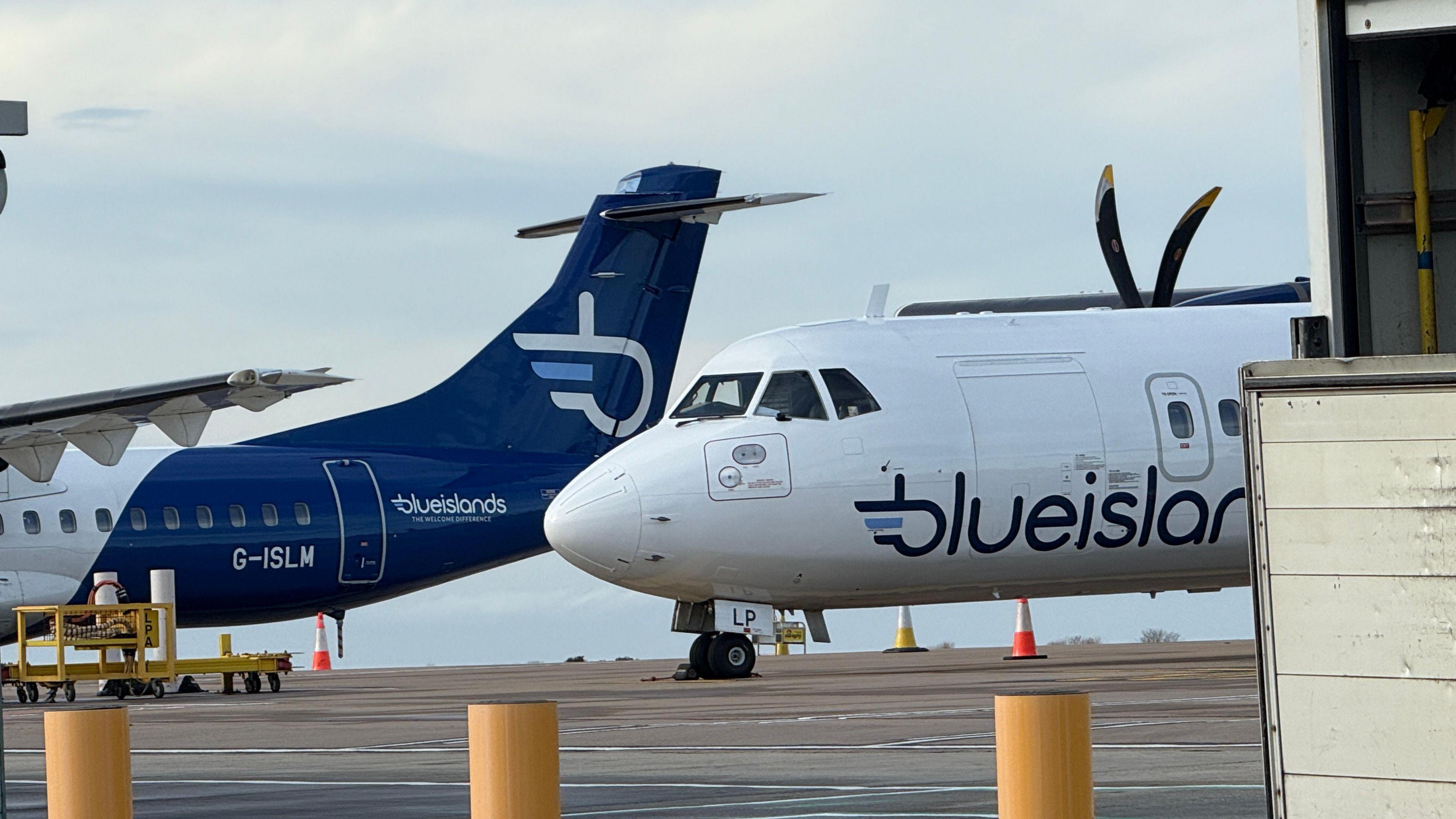 Two Blue Islands aircrafts on the tarmac at Guernsey Airport. Clouded blue skies can be seen behind.