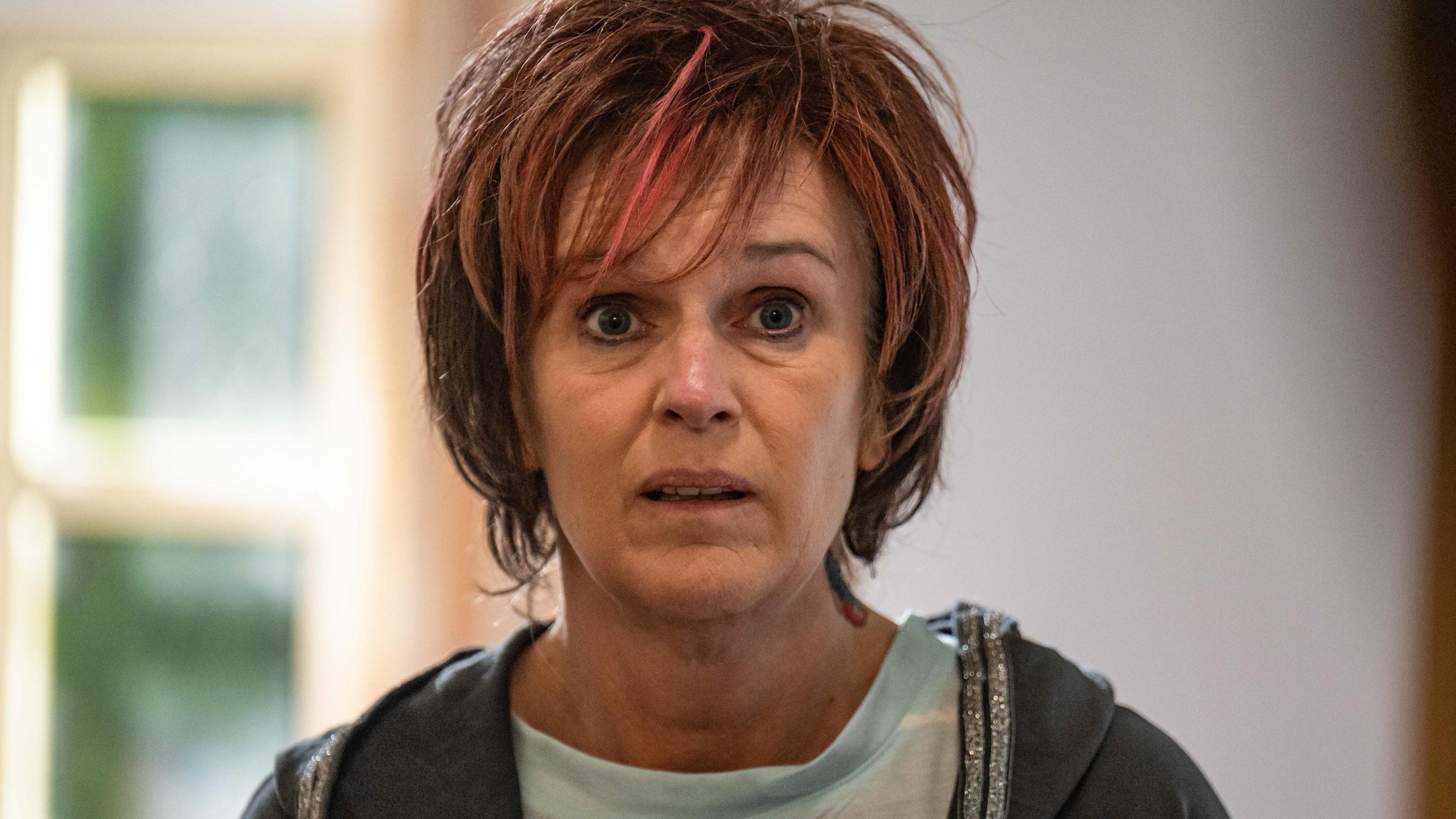 Siobhan Finneran as Lin in Alma's Not Normal - she has dyed reddish-brown short hair, and is waring a mint green t-shirt and grey hoodie