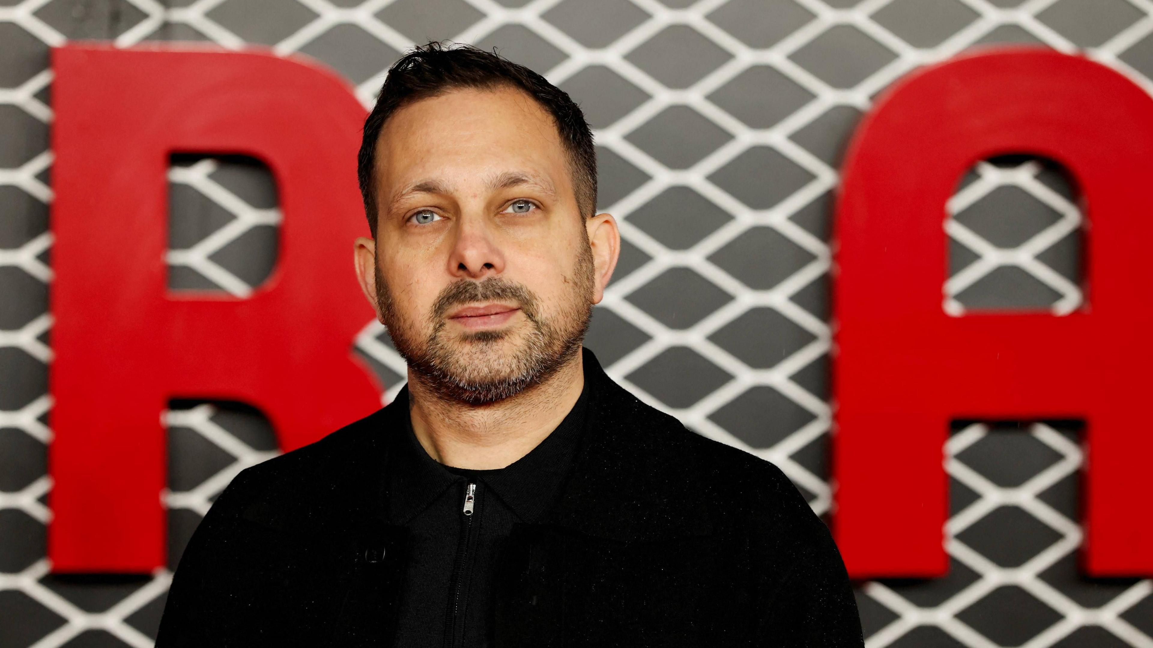 Bradford-born magician Steven Frayne, formerly known as Dynamo, stands in front of red lettering