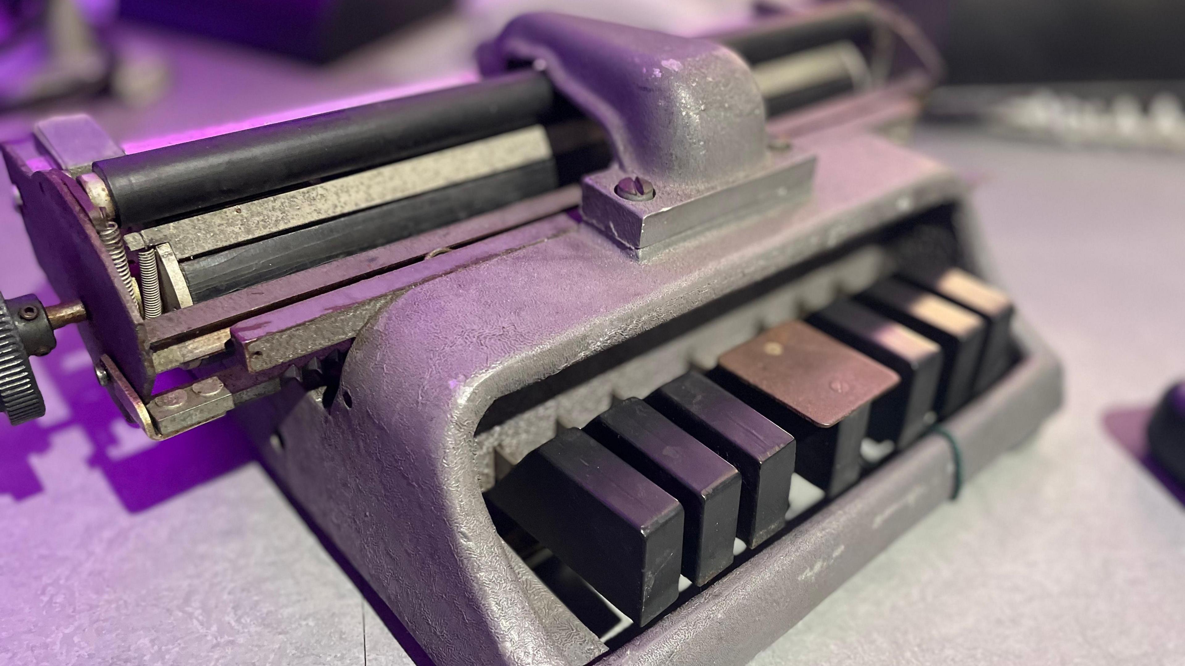 A Braille typewriter. A metal machine with six keys.