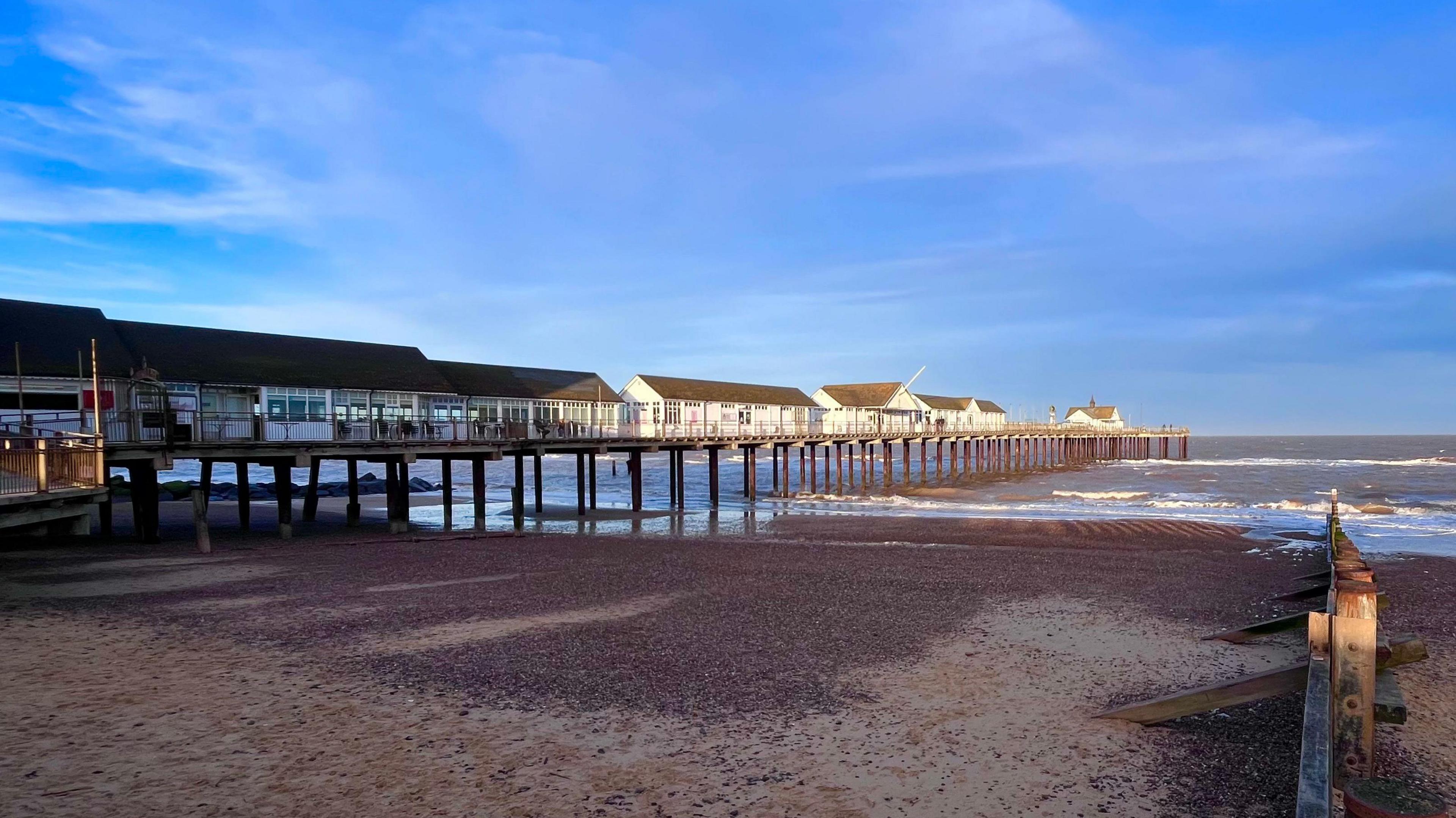 A general view of Southwold Pier extending out into the sea. White buildings line the pier.