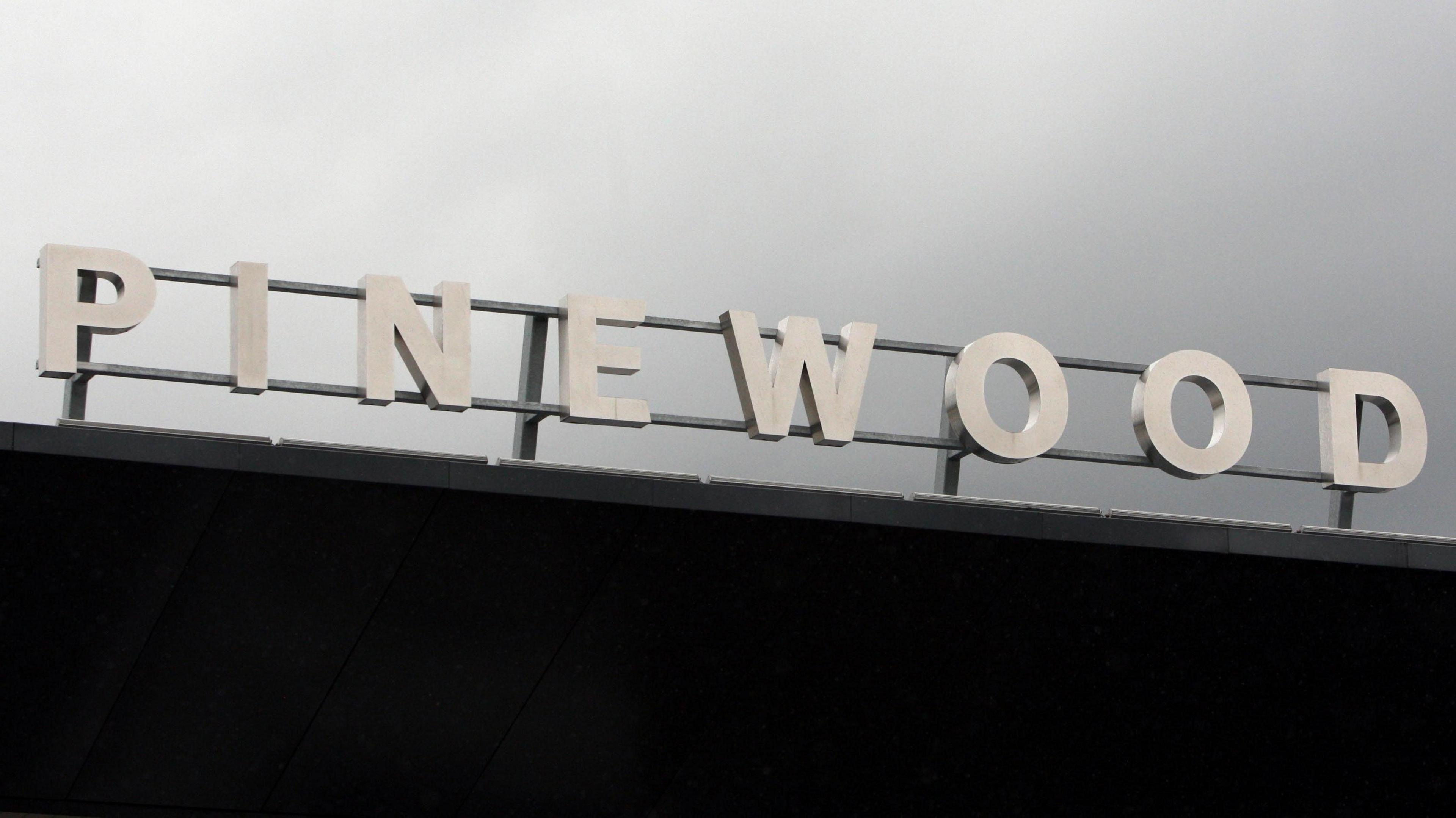 The Pinewood sign, on top of the studios building, on a grey and cloudy day.