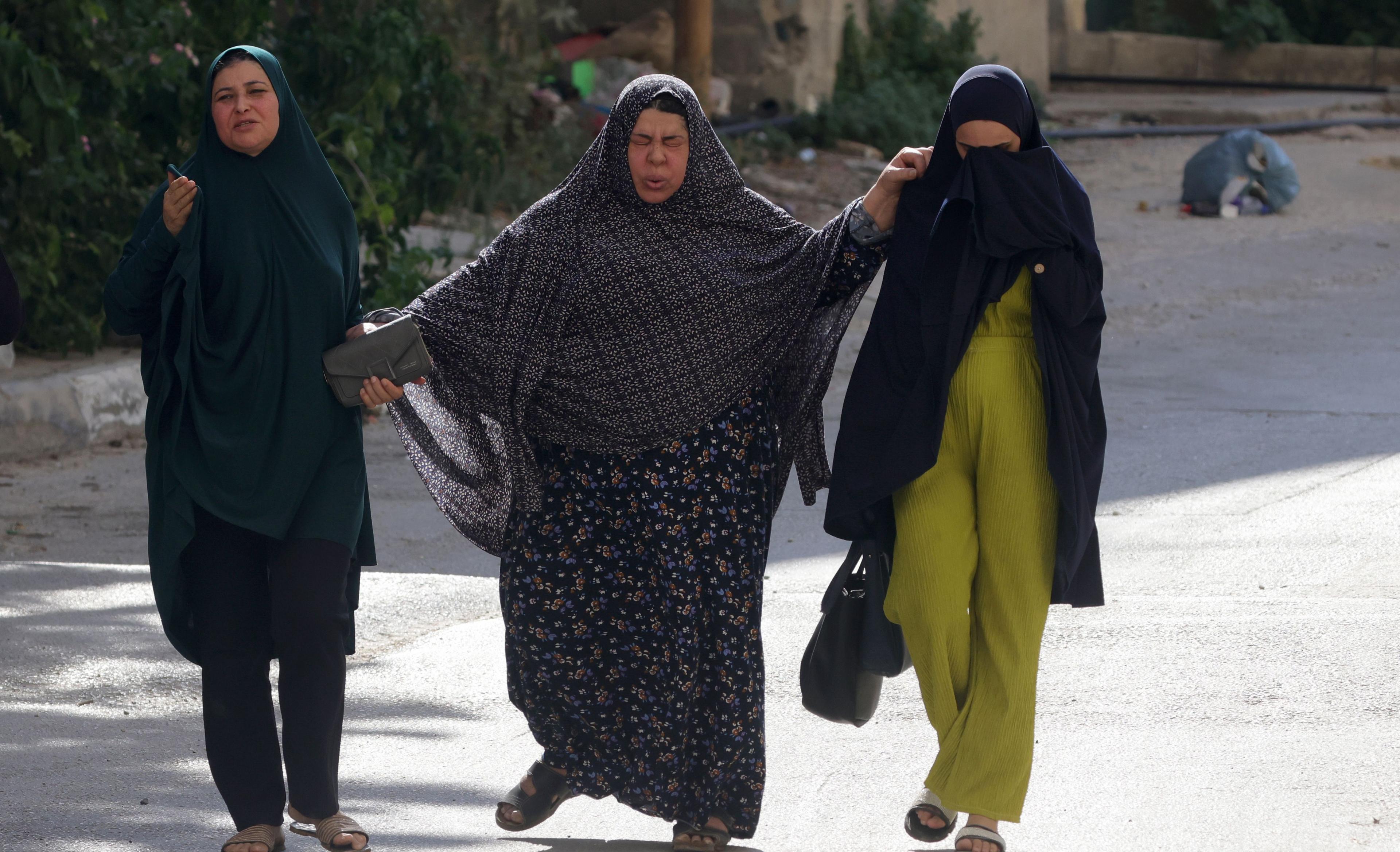 Palestinian women walk past Israeli troops as they leave Jenin refugee camp, 31 August