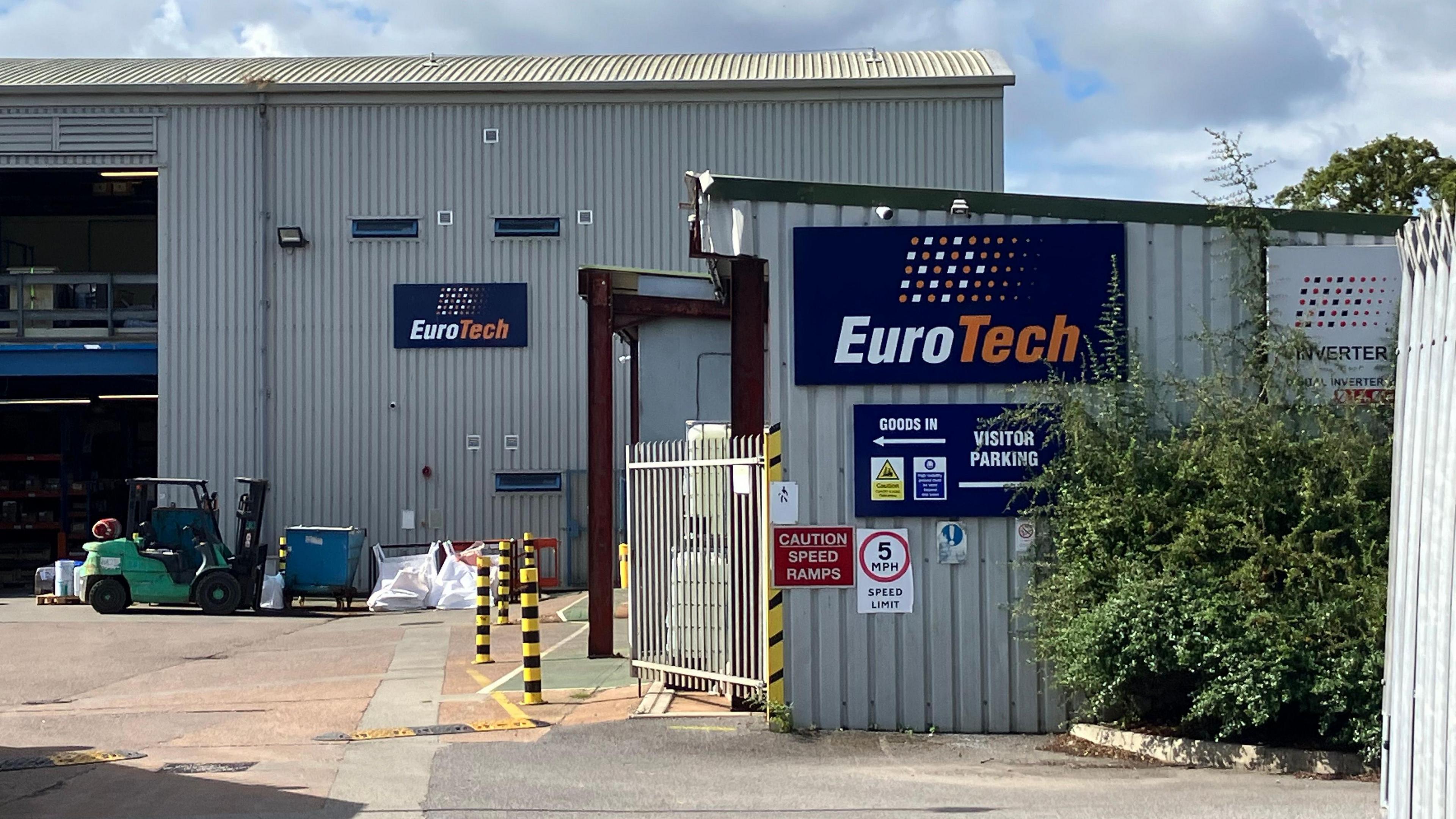 Eurotech's base in Exmouth. Large white gates are open and leading into buildings with blue Eurotech signs on them.