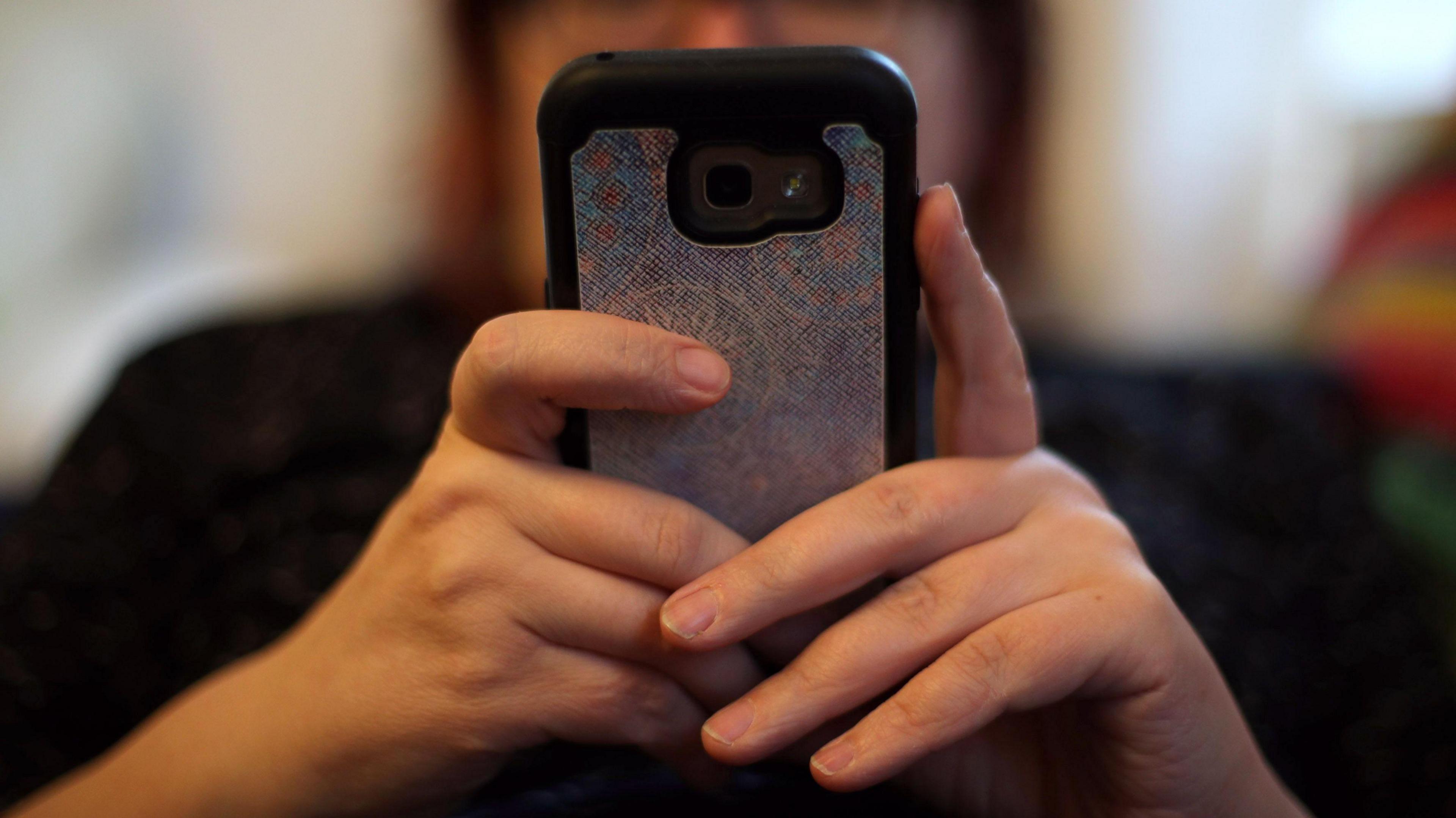 A woman is holding up a smart phone 