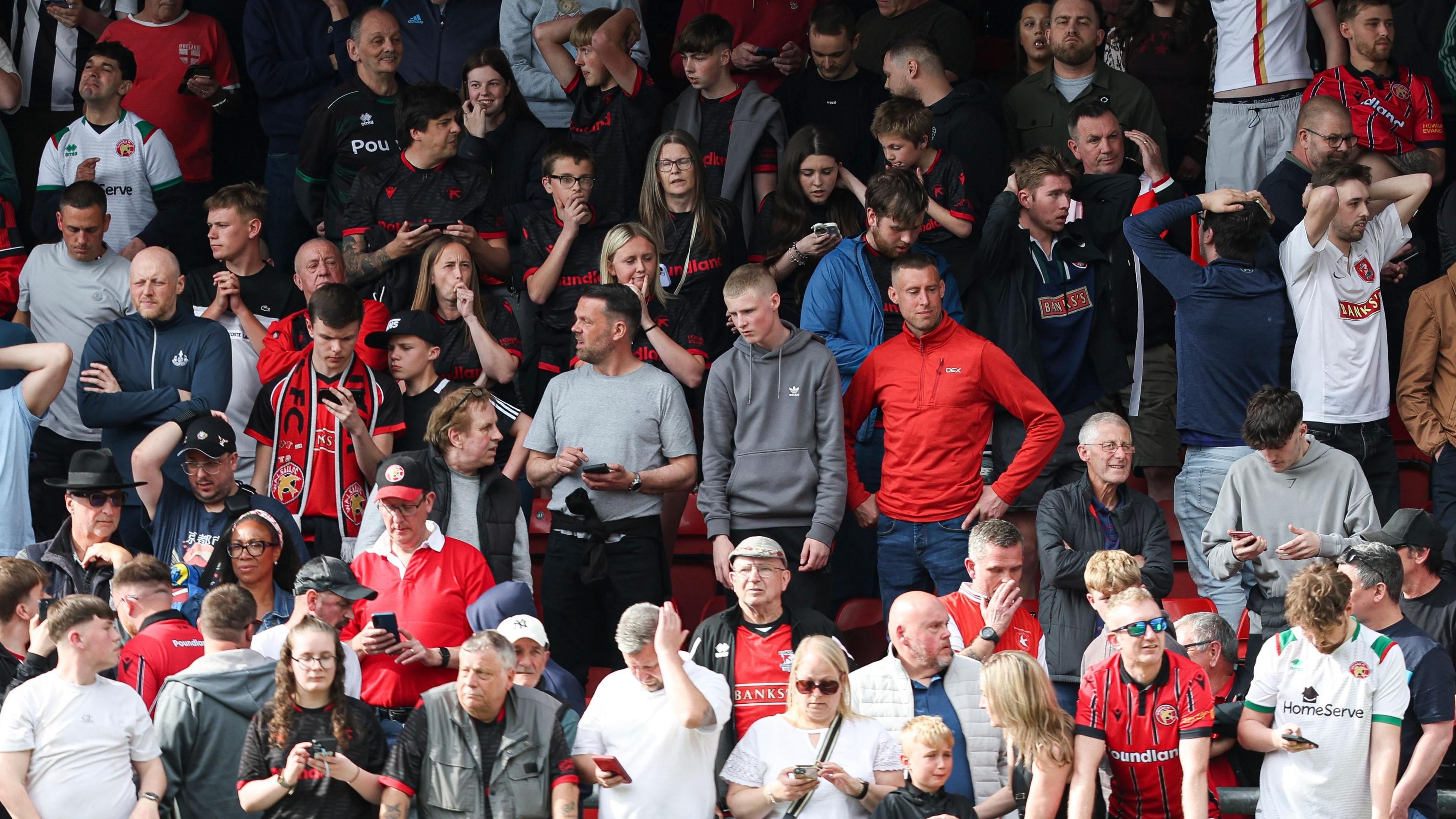 A close up of Walsall fans in the stand looking dejected after learning the side had missed out on automatic promotion on the final day of the season