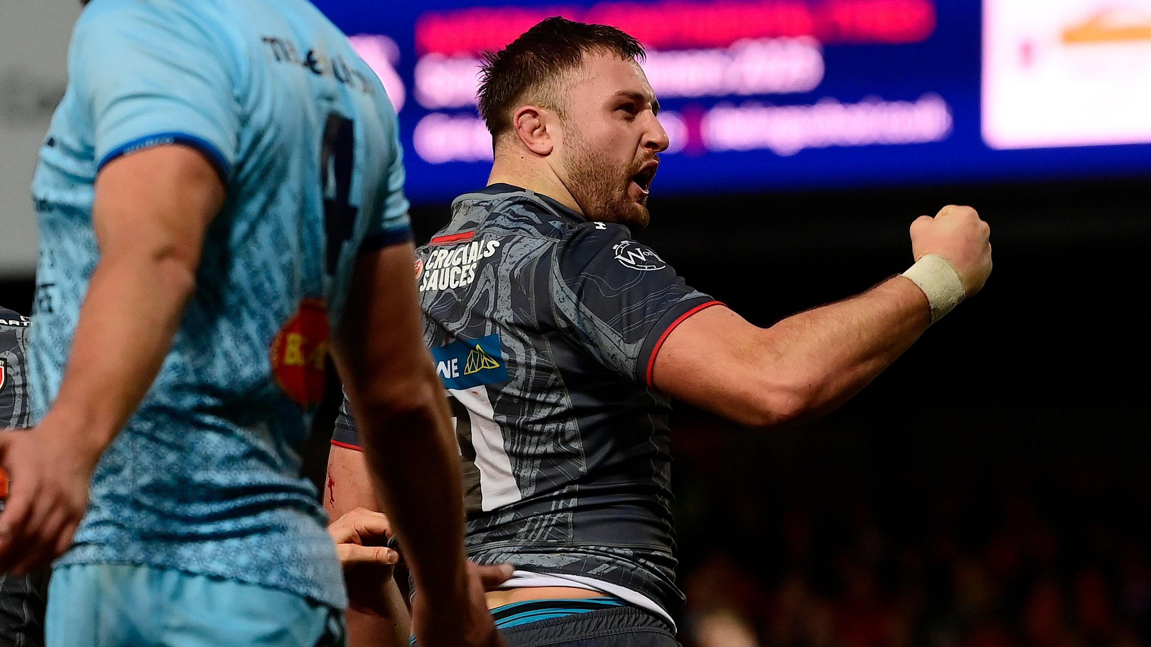 Gloucester back-row forward Will Trenholm punches the air and roars at crowd in a grey and black away kit