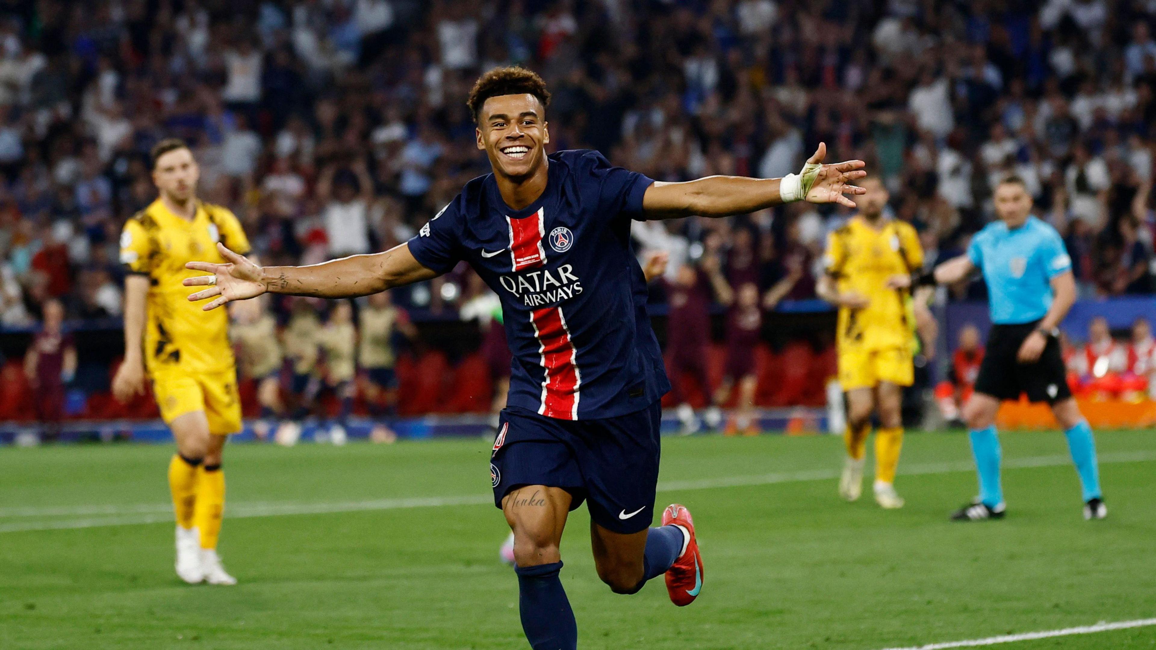 Desire Doue runs and holds his arms out in celebration of a goal