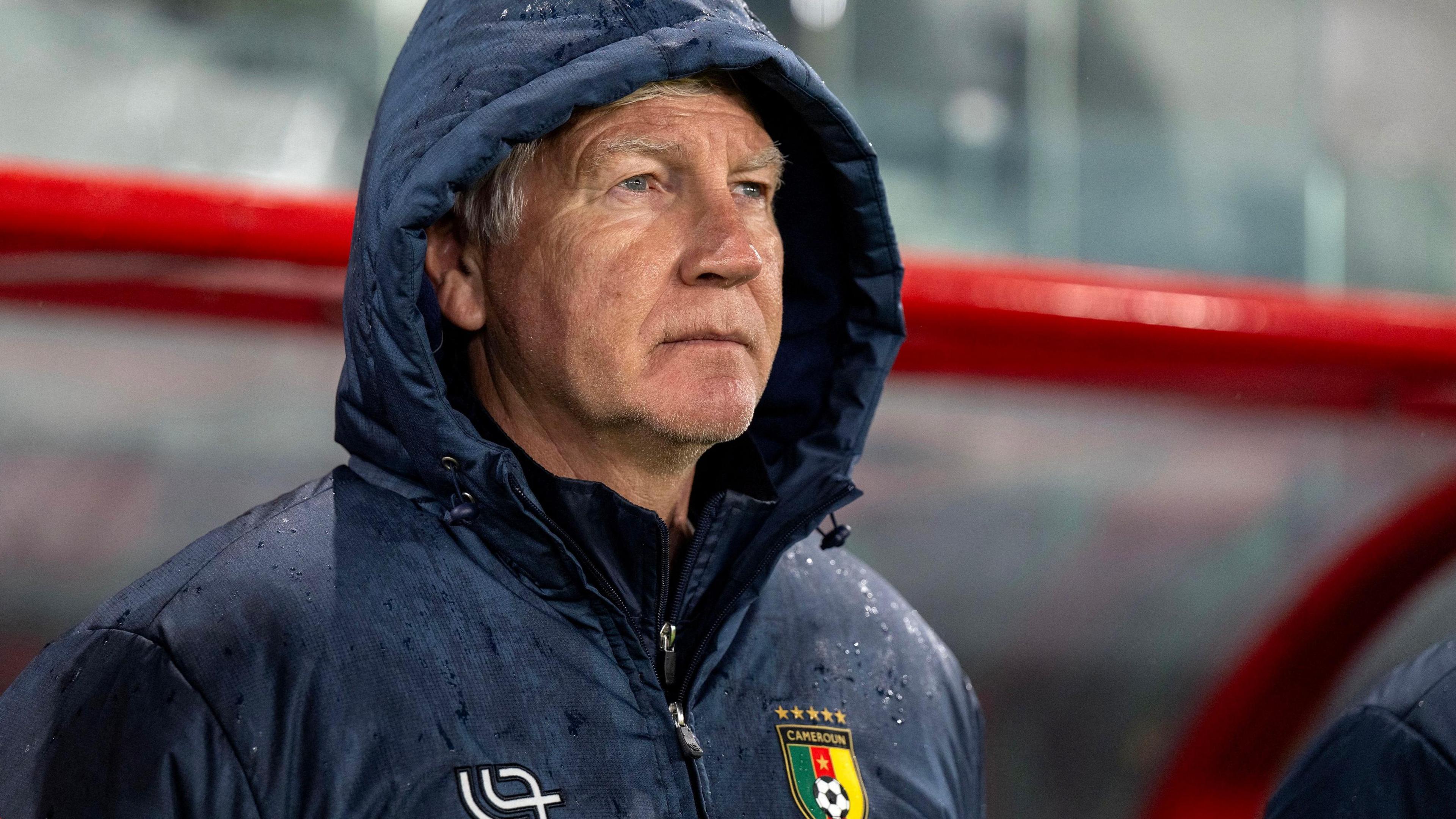 Marc Brys wears a dark blue Cameroon rain jacket with the hood up