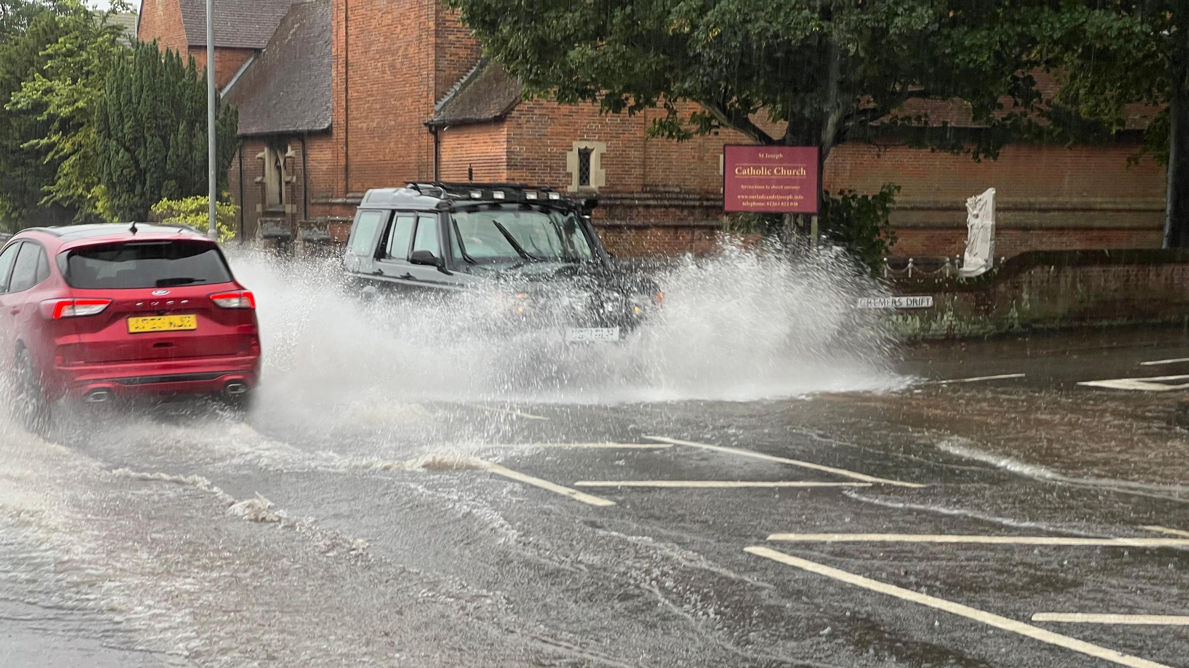 A photo of two cars driving through floodwaters in Norfolk