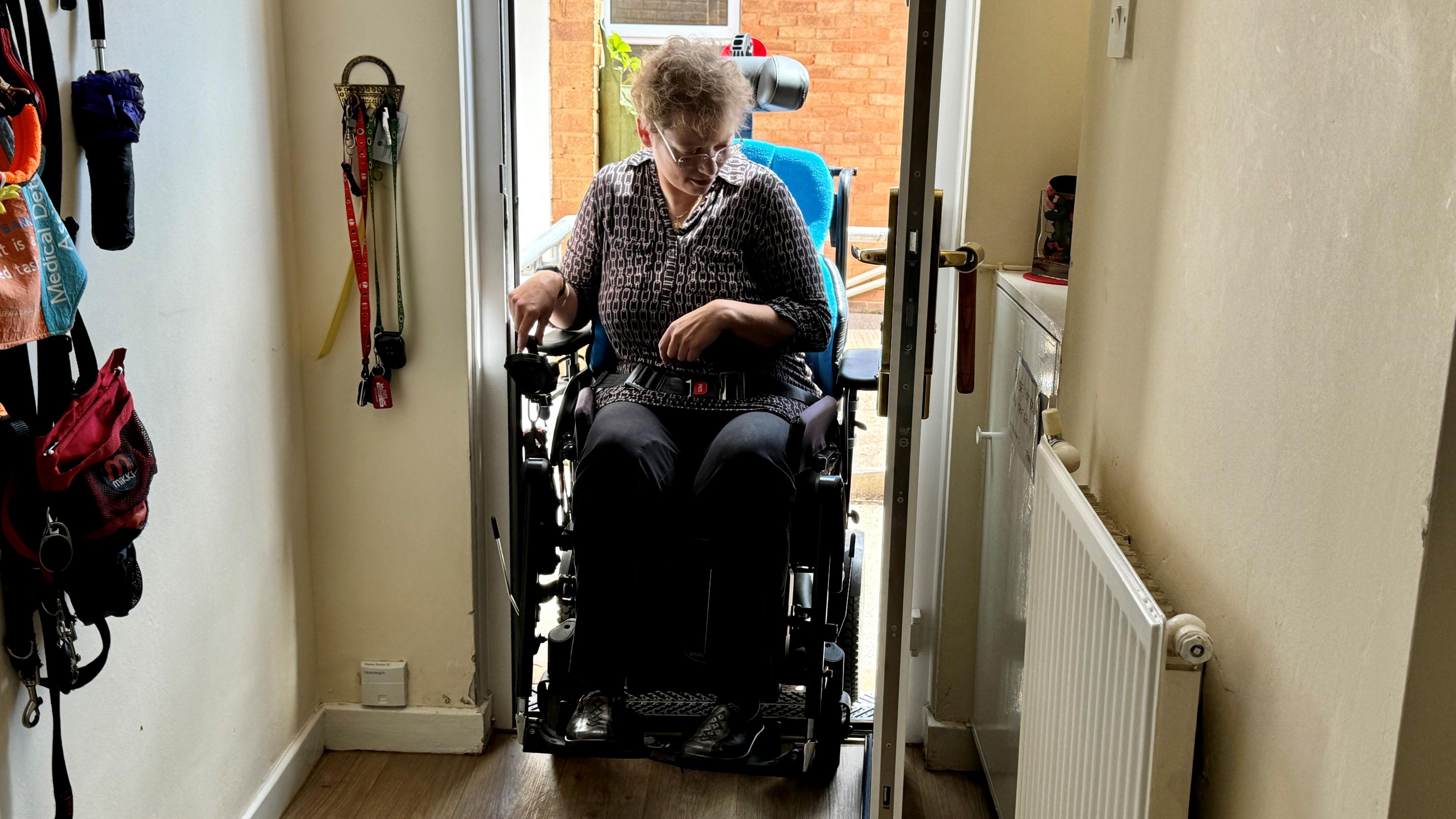 Sarah Lambert coming through door in wheelchair