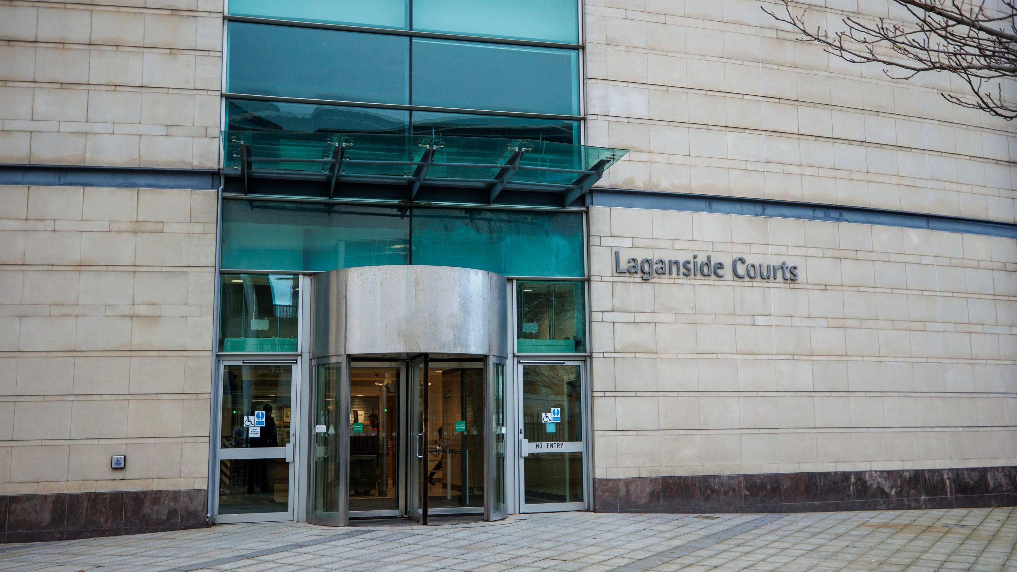 Belfast court. The entrance doors, the building is large and made of beige stone with a brown bottom. 