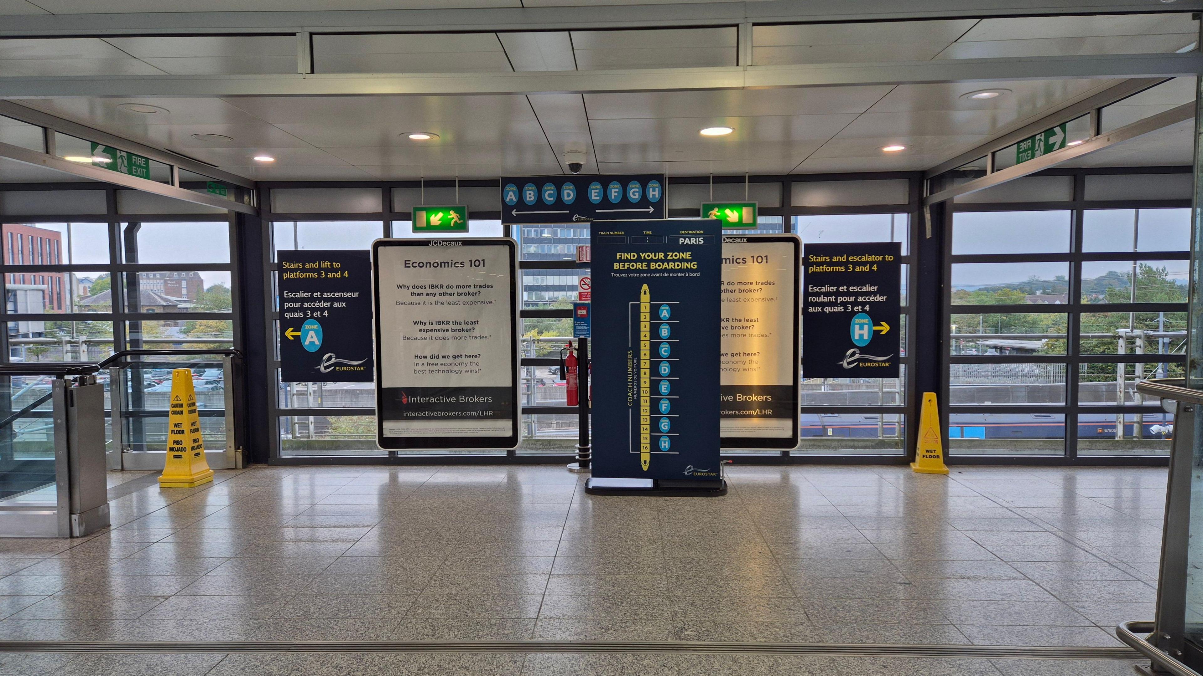 The inside of the Ashford International rail terminal, with polished stone floor and signs welcoming passengers.