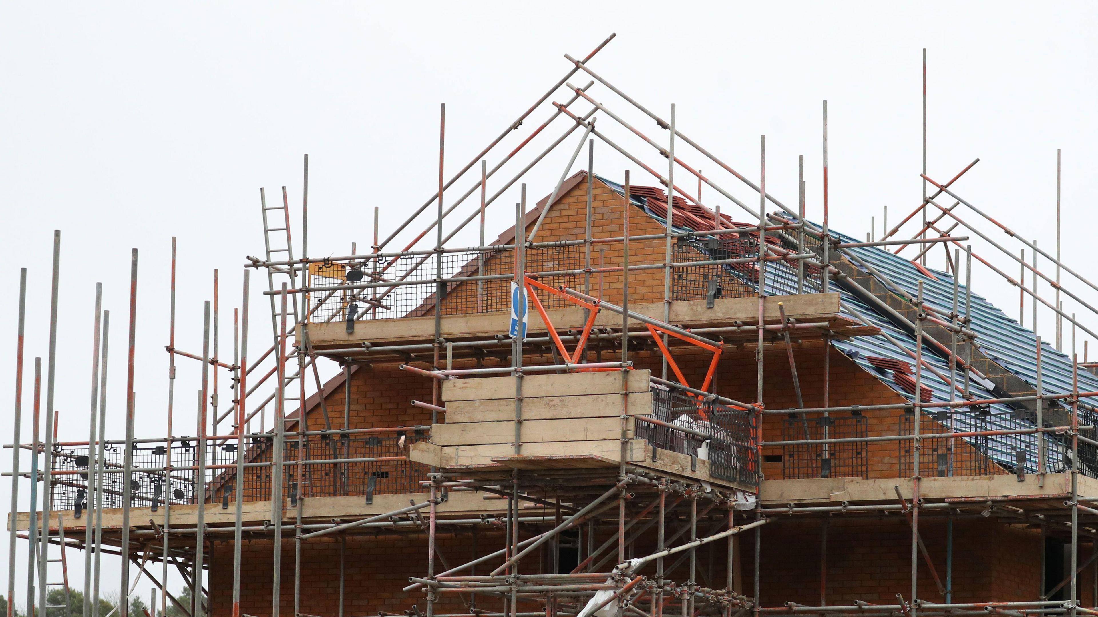 A house surrounded by scaffolding on a grey day.