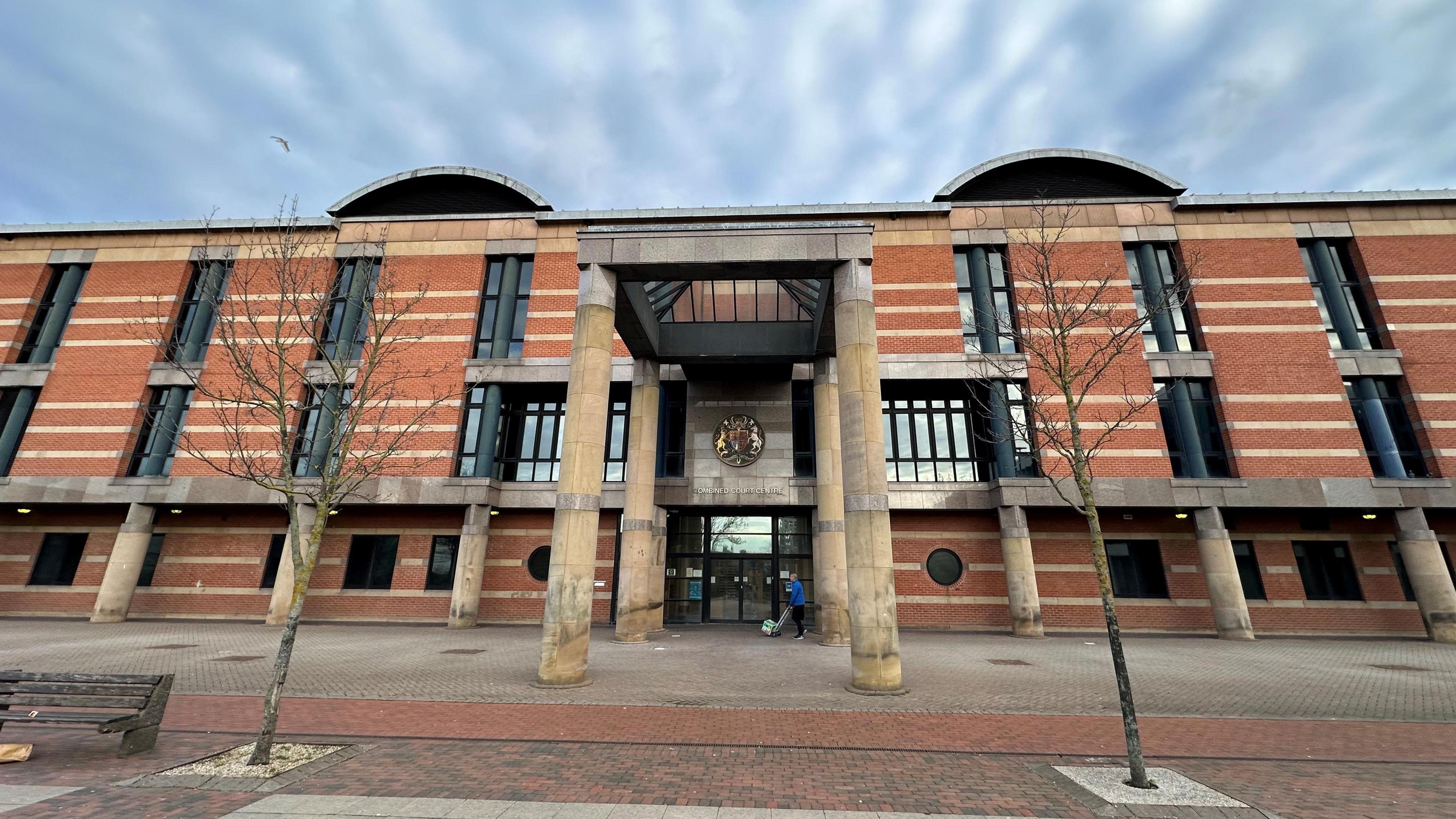 A large red brick court building with two stone columns either side of the front door