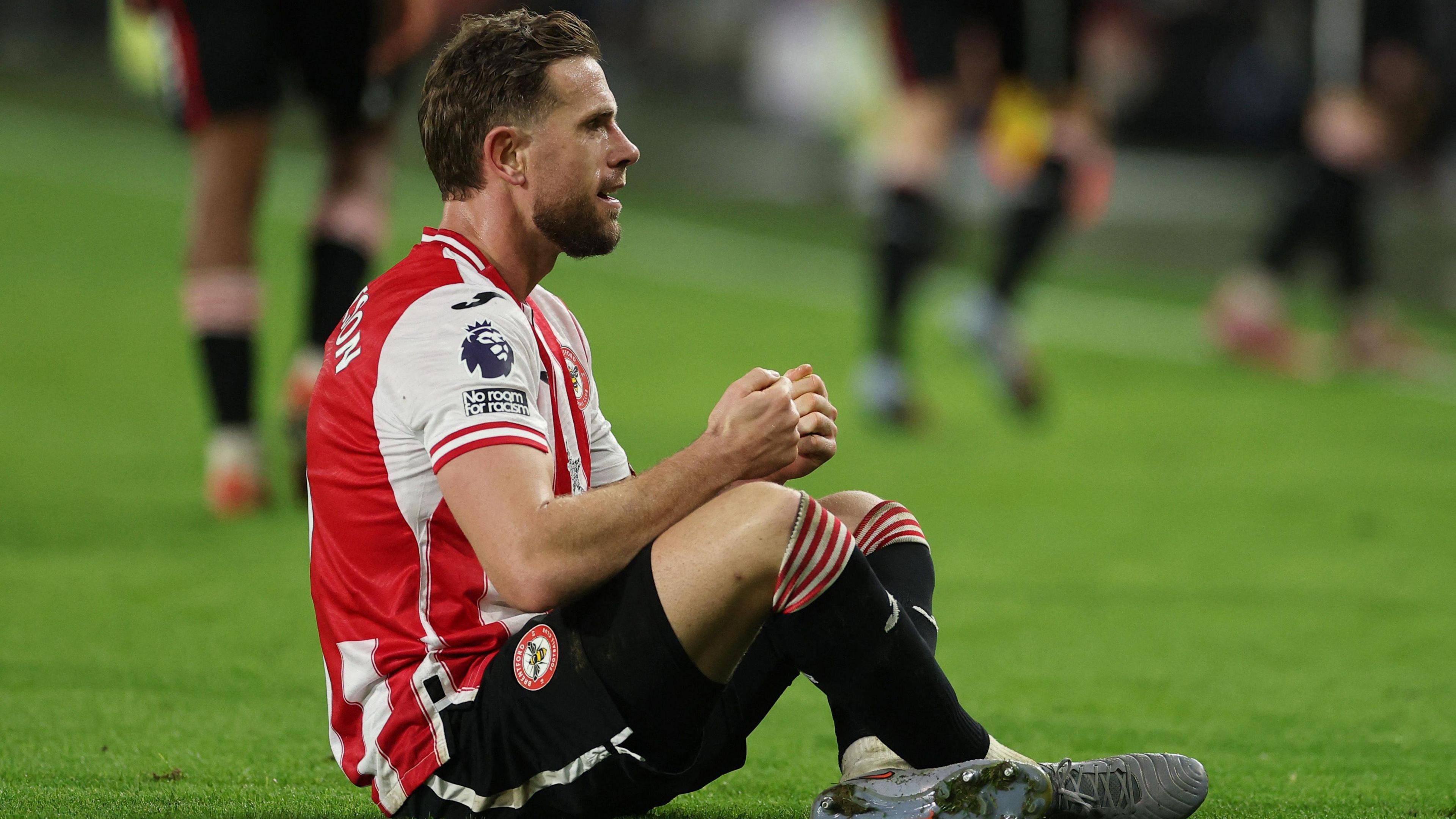 Jordan Henderson sits on the floor and pretends to play a computer game