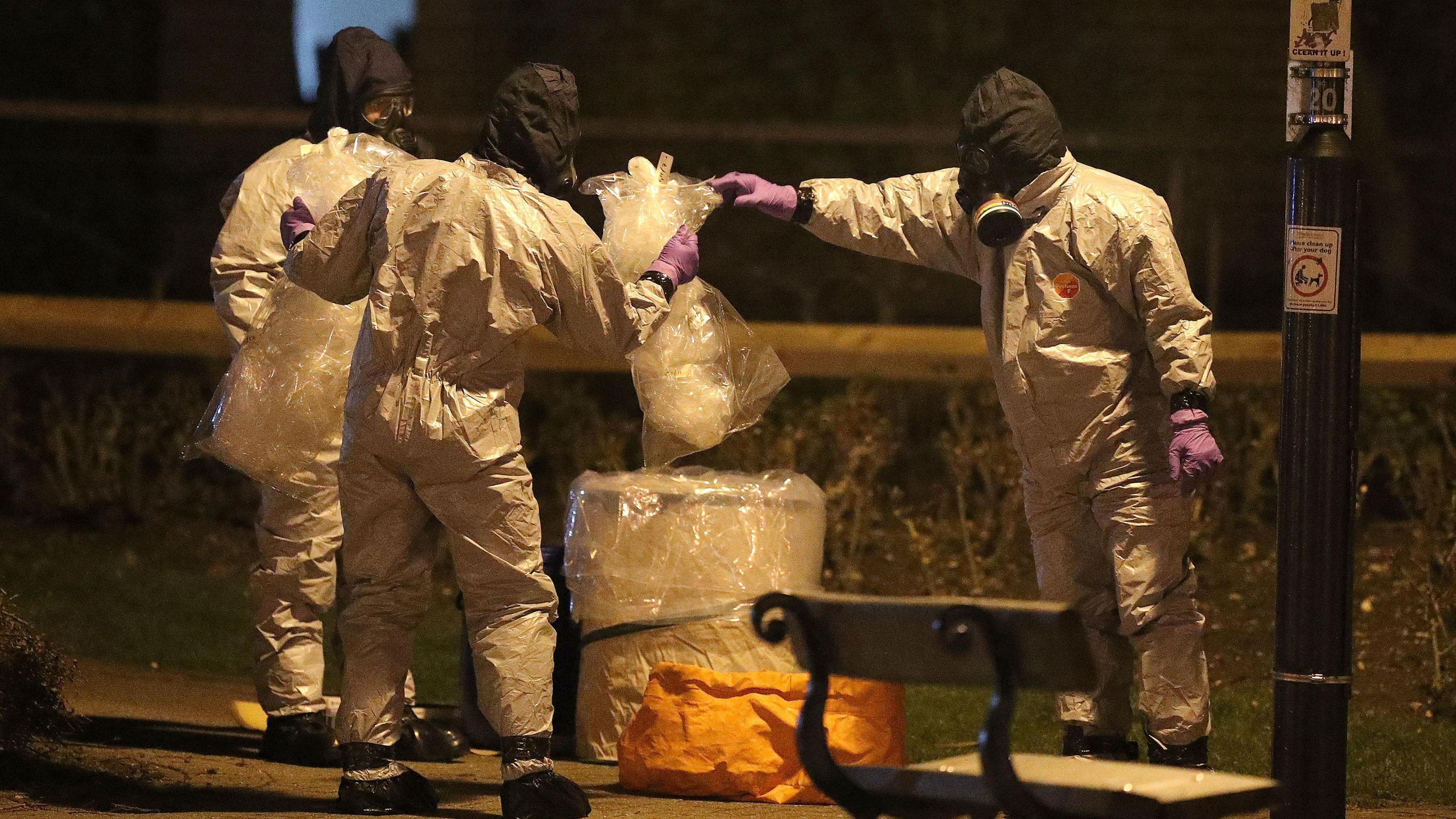 People wearing protective suits put a plastic bag in a bin, near the Maltings shopping centre in Salisbury, where former Russian double agent Sergei Skripal and his daughter Yulia, were found critically ill by exposure to Novichok nerve agent.