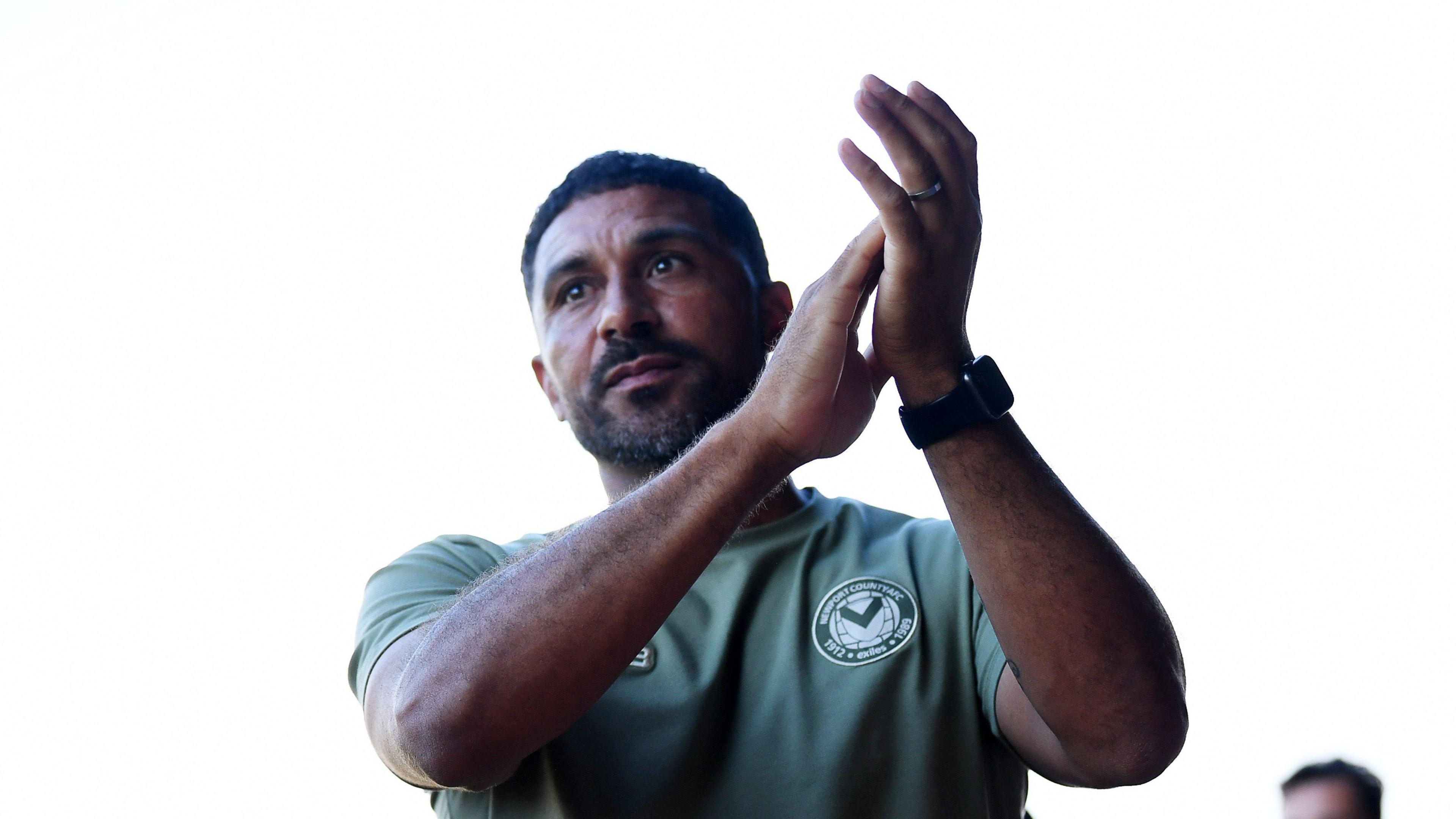 Newport County boss Hayden Mullins applauds supporters.