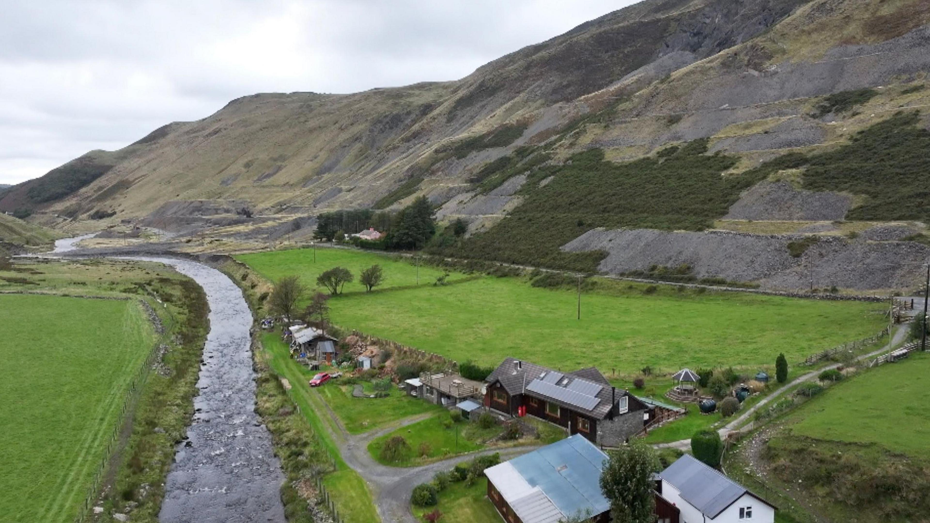 An aerial shot of the River Ystwyth valley. The river is on the left of the photo and there are houses in the green fields to the right of photo. 