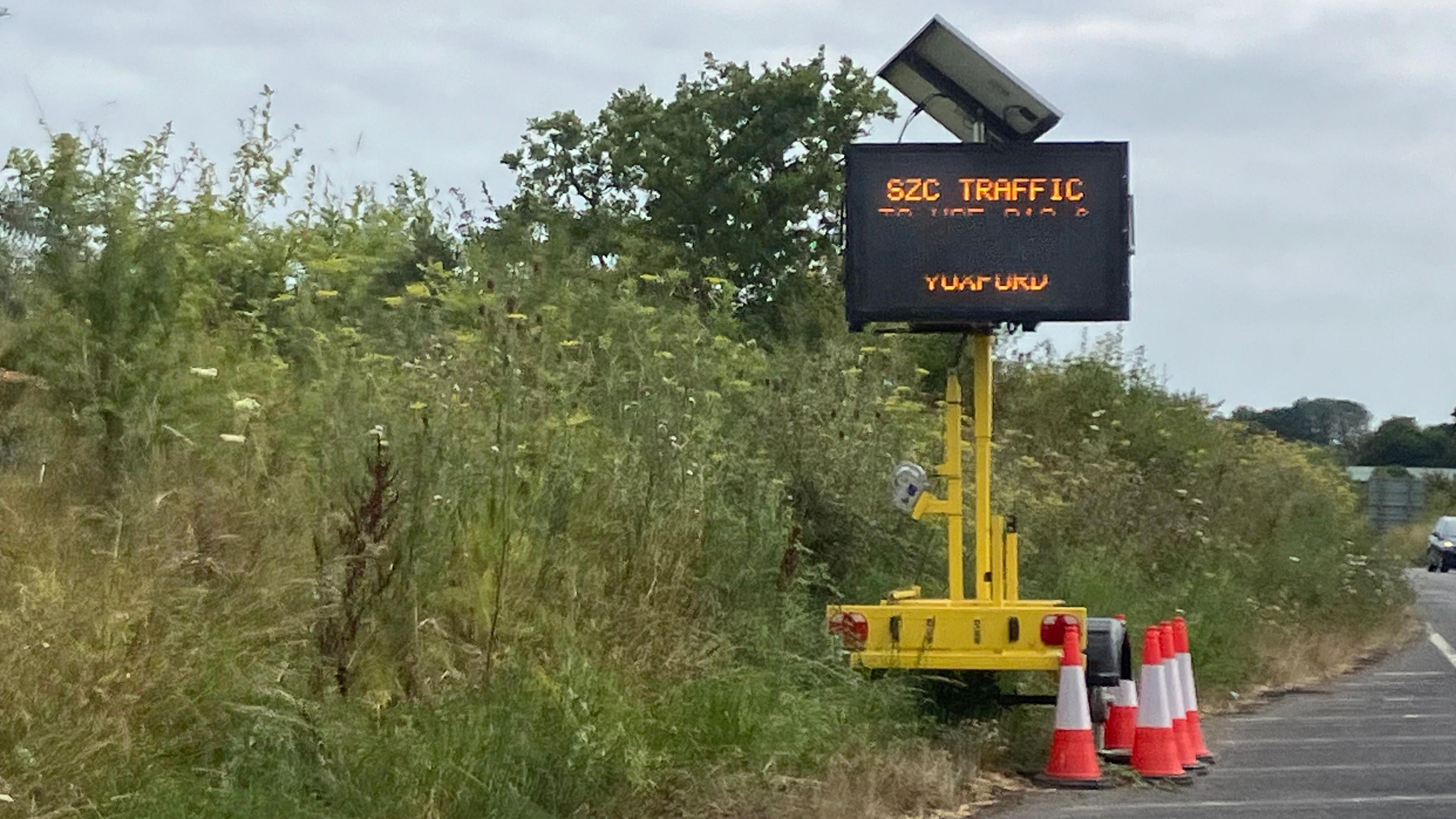 A yellow electronic road sign beside the A 12 has messages for "SZC Traffic" 