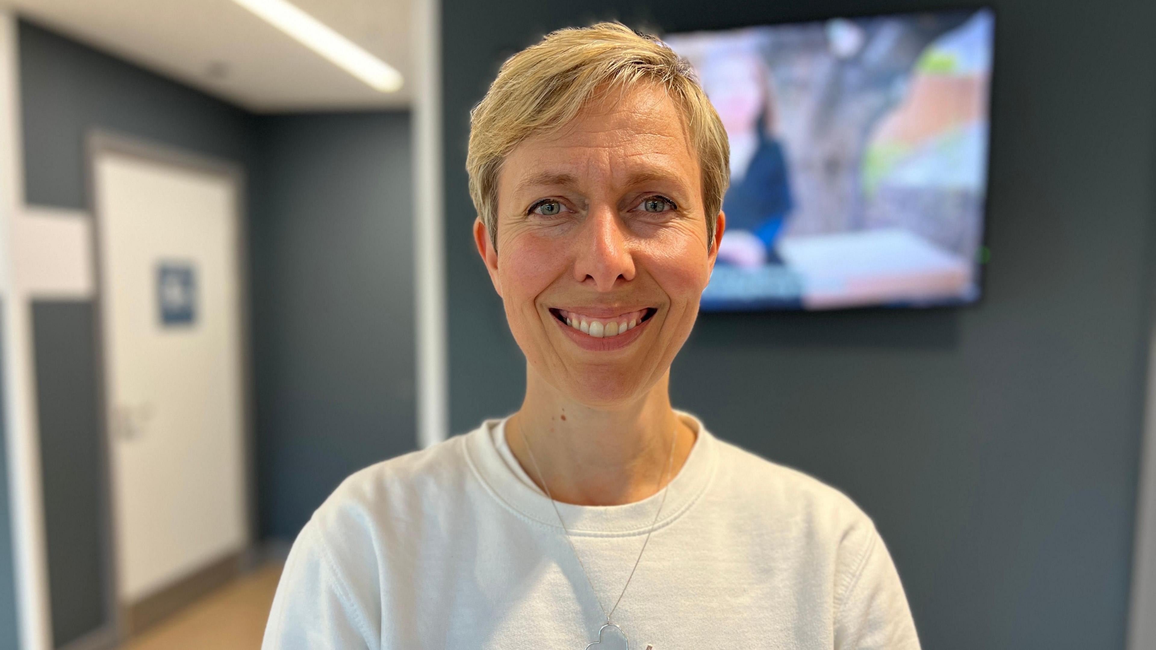 Laura Gelder-Robertson who has short hair and is wearing a white jumper, smiling