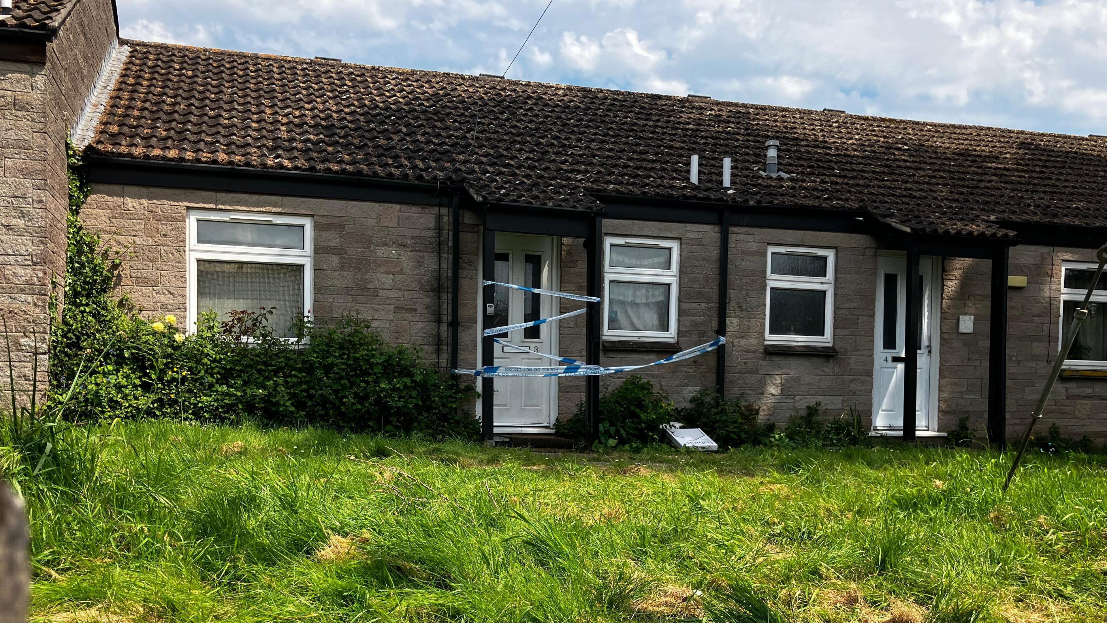 Image of the murder scene in Baltonsborough. Police crime scene tape is hung across the door. 